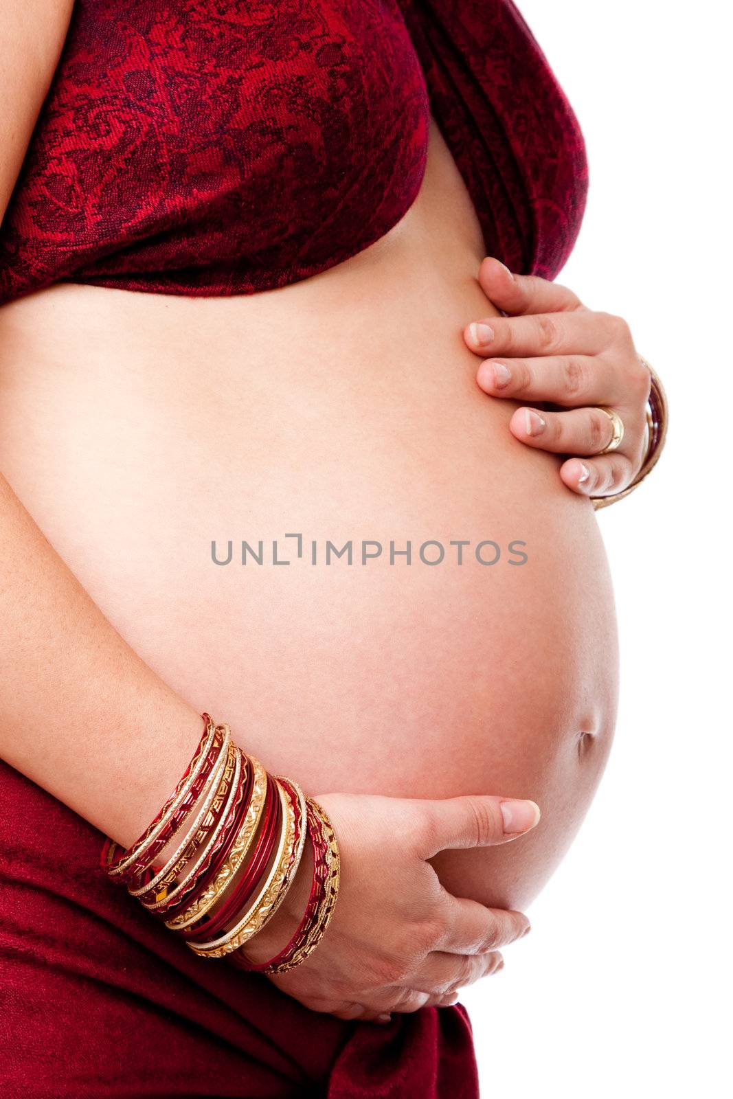 Pregnant woman holding her belly, dressed in red and gold with red bracelets on her arm, isolated.