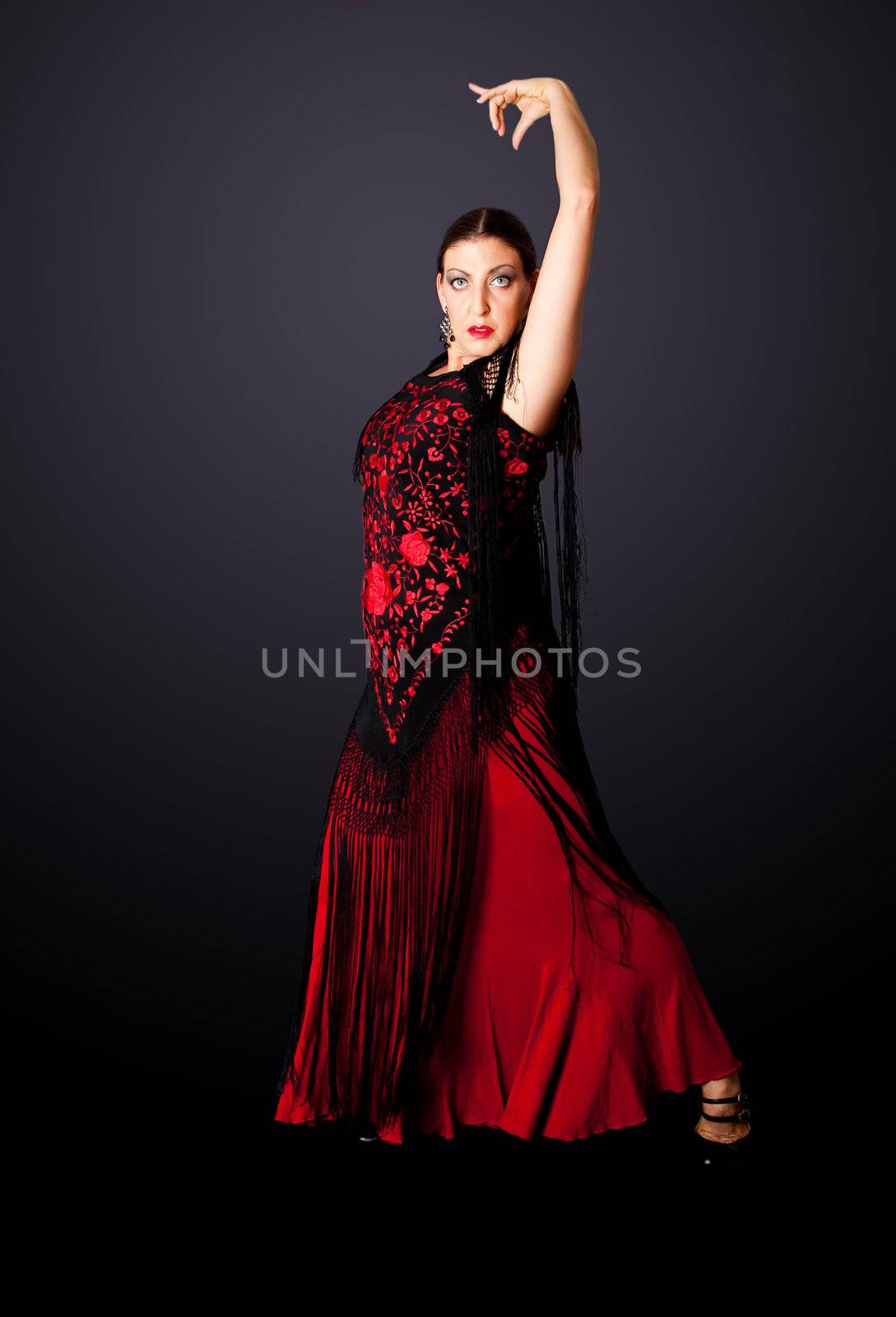 Beautiful female Spanish Flamenco dancer doing a typical line pose, wearing modern attire. Spanish woman dancing Paso Doble in red and black dress clothes, isolated.