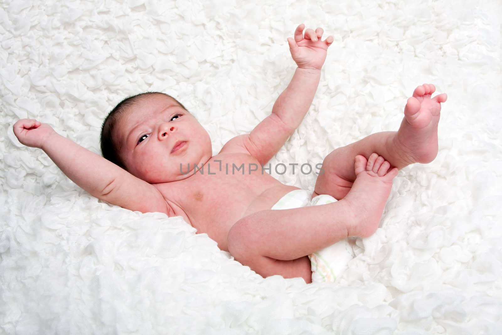 Happy Caucasian Hispanic infant baby falling on soft white cotton cloud with arms and legs in the air.