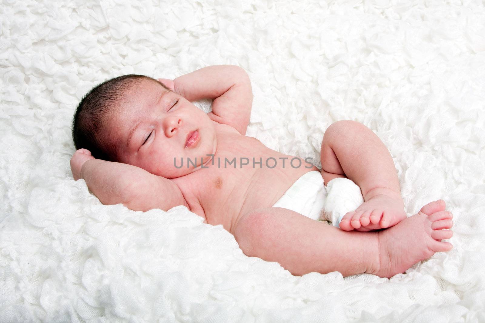 Cute Caucasian Hispanic infant baby asleep on soft white cotton cloud, wearing only a diaper.
