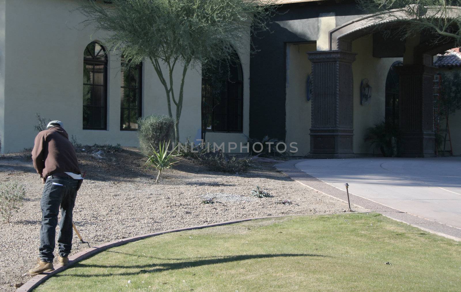 Man cleaning landscaping of a upscale home