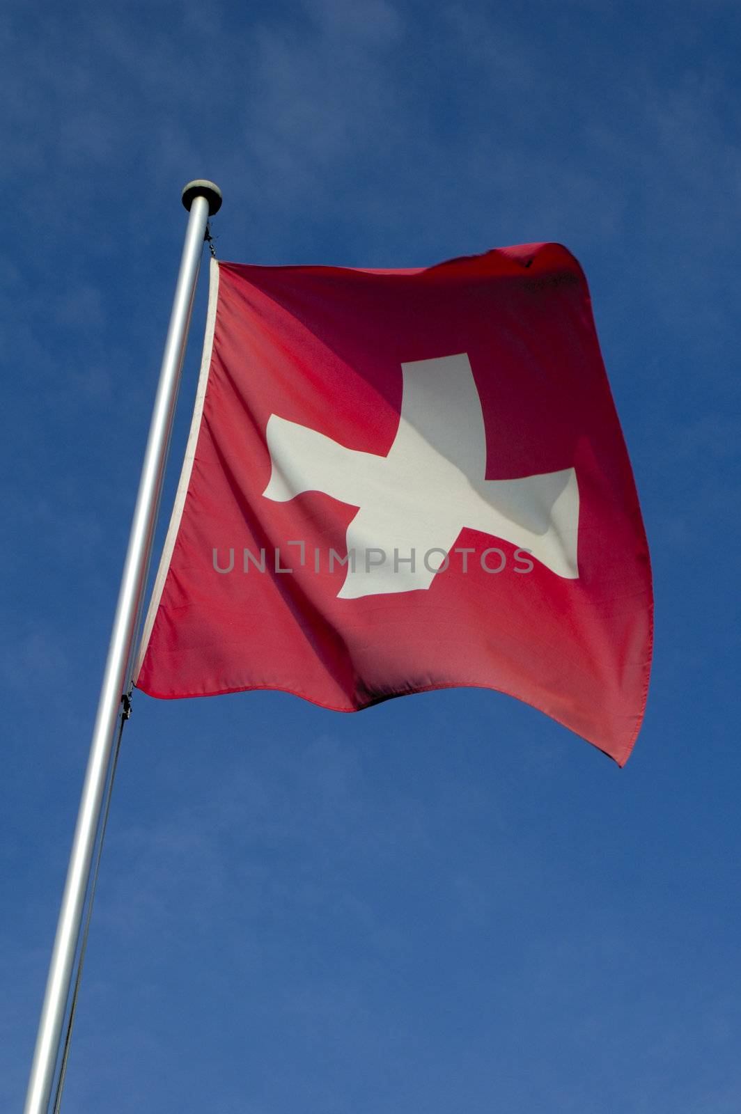 The flag of Switzerland flying against a blue sky.