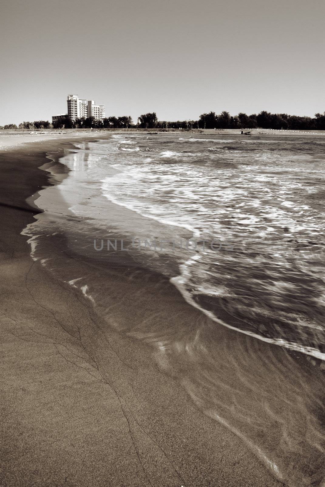 Landscape of beach and coastline with wave motion and dramatic sky.