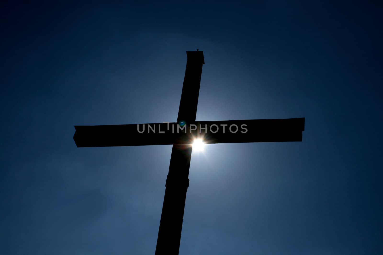 a cross with the sun behind it