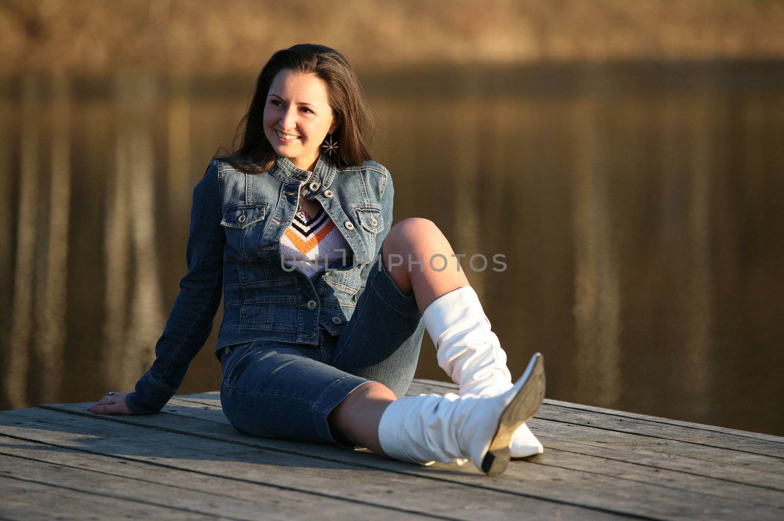 The laughing brunette sits on the wooden bridge at the river