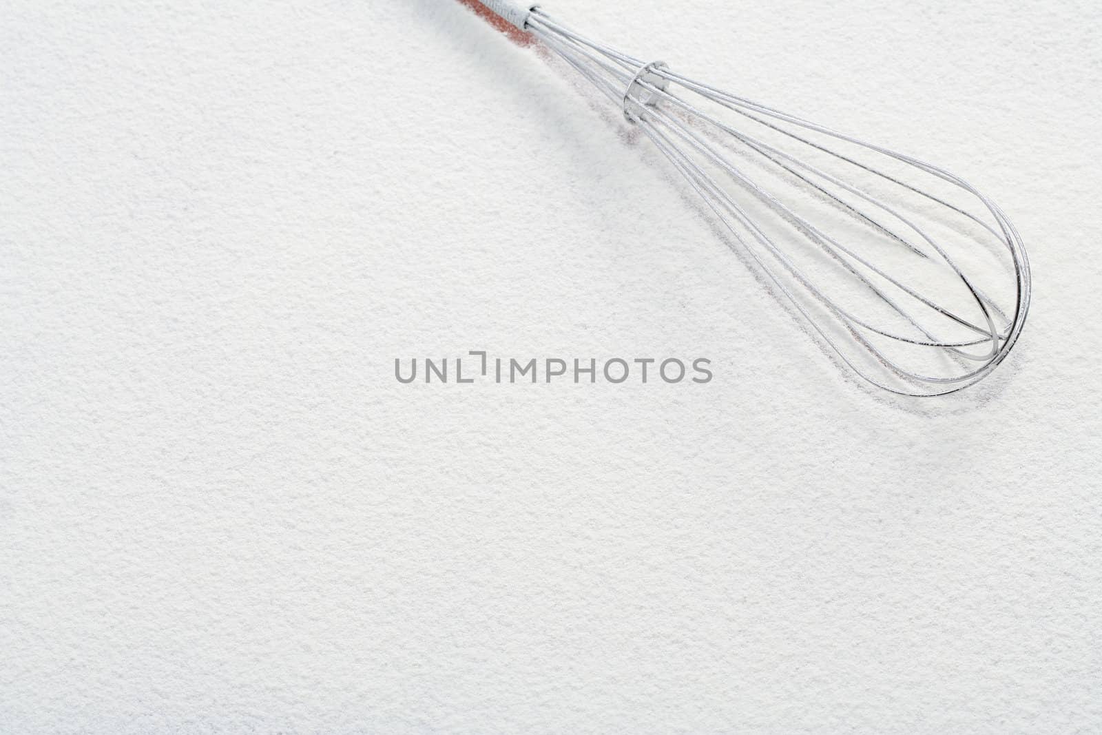 Wire whisk on flour, background 