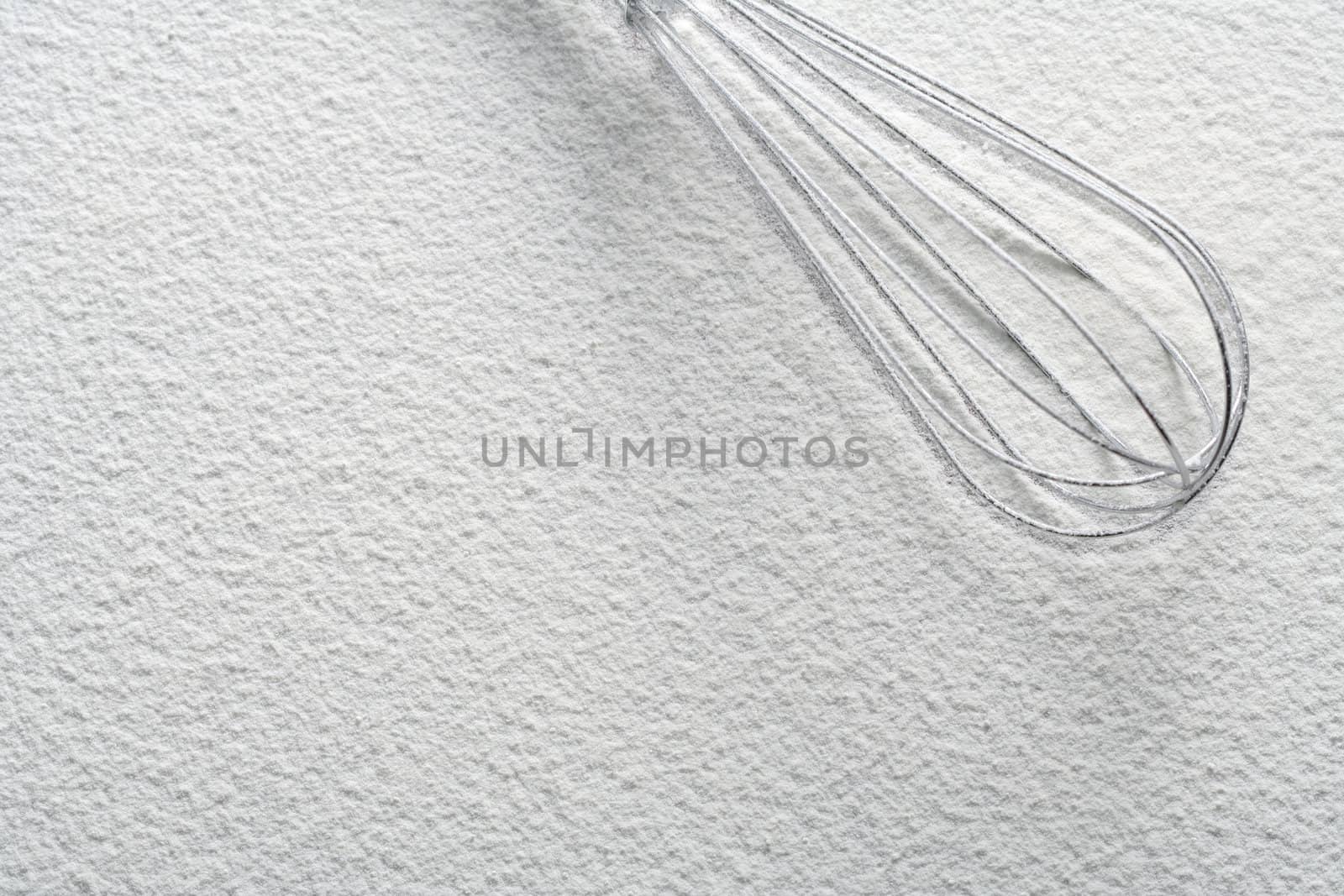 Wire whisk on flour, background 