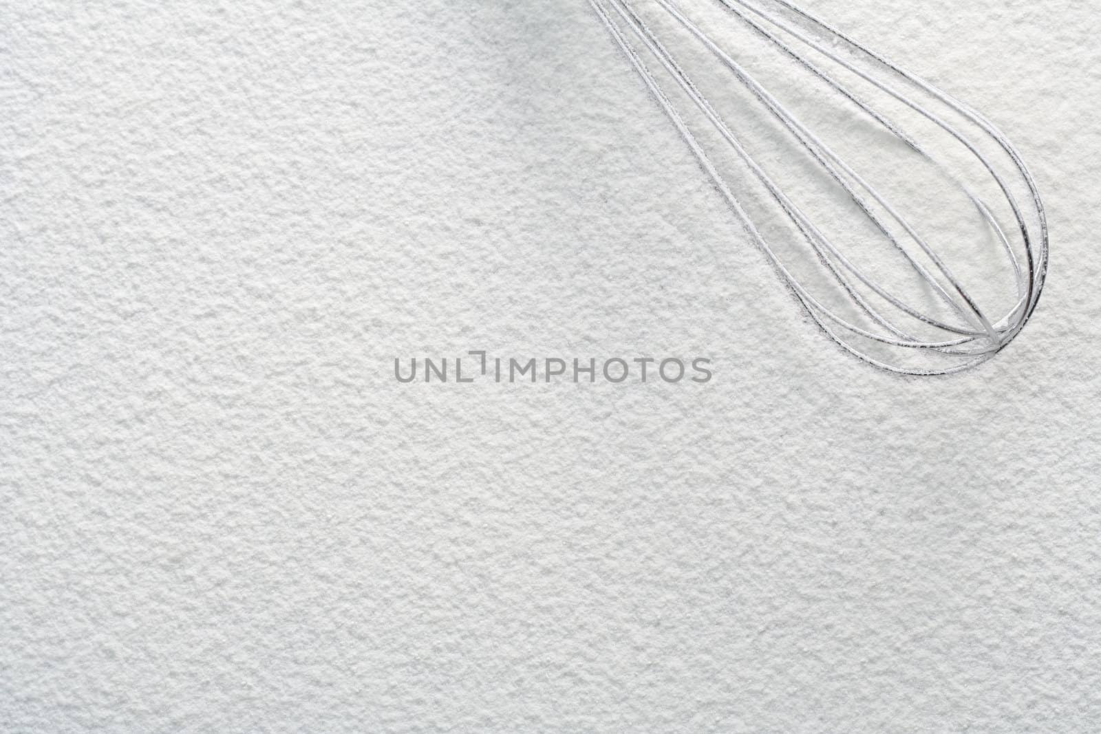Wire whisk on flour, background 