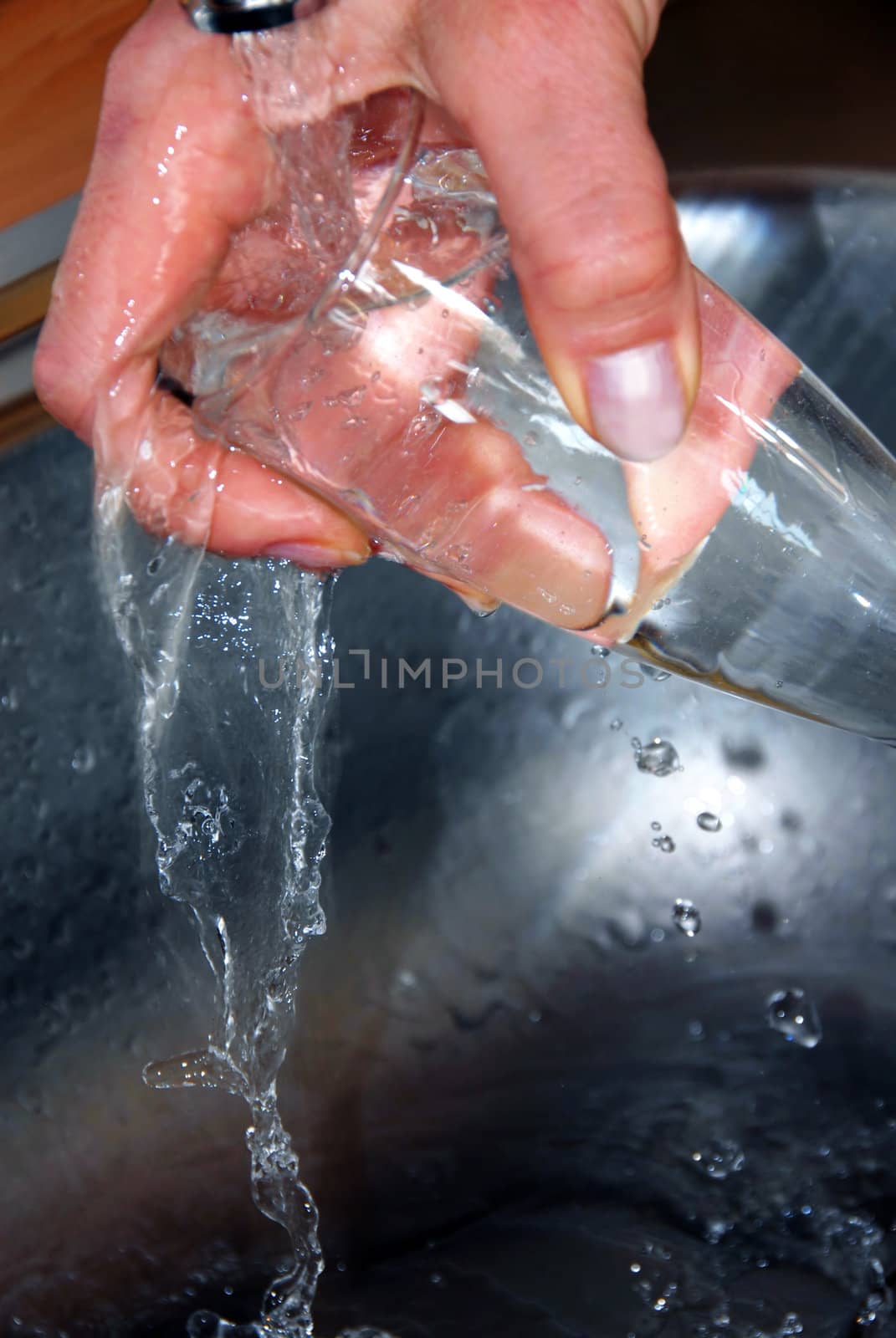 hand washing wineglass in water in sink