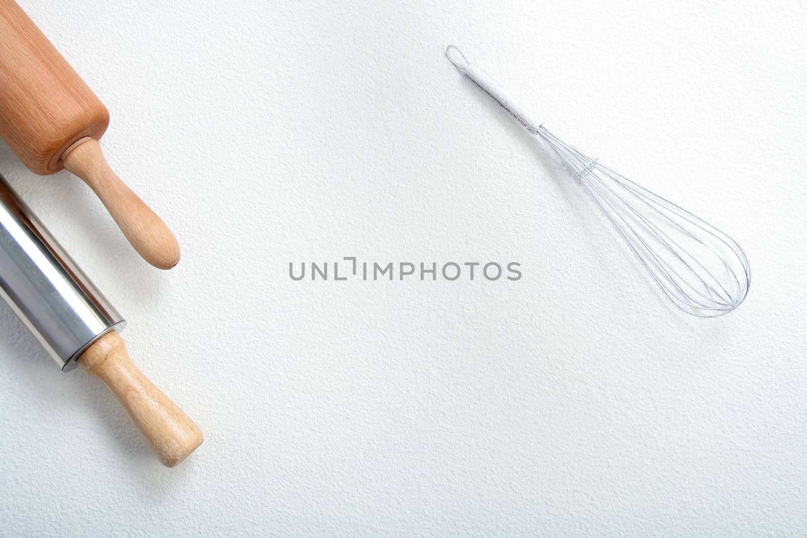 Wire whisk and rolling pin on flour, background 
