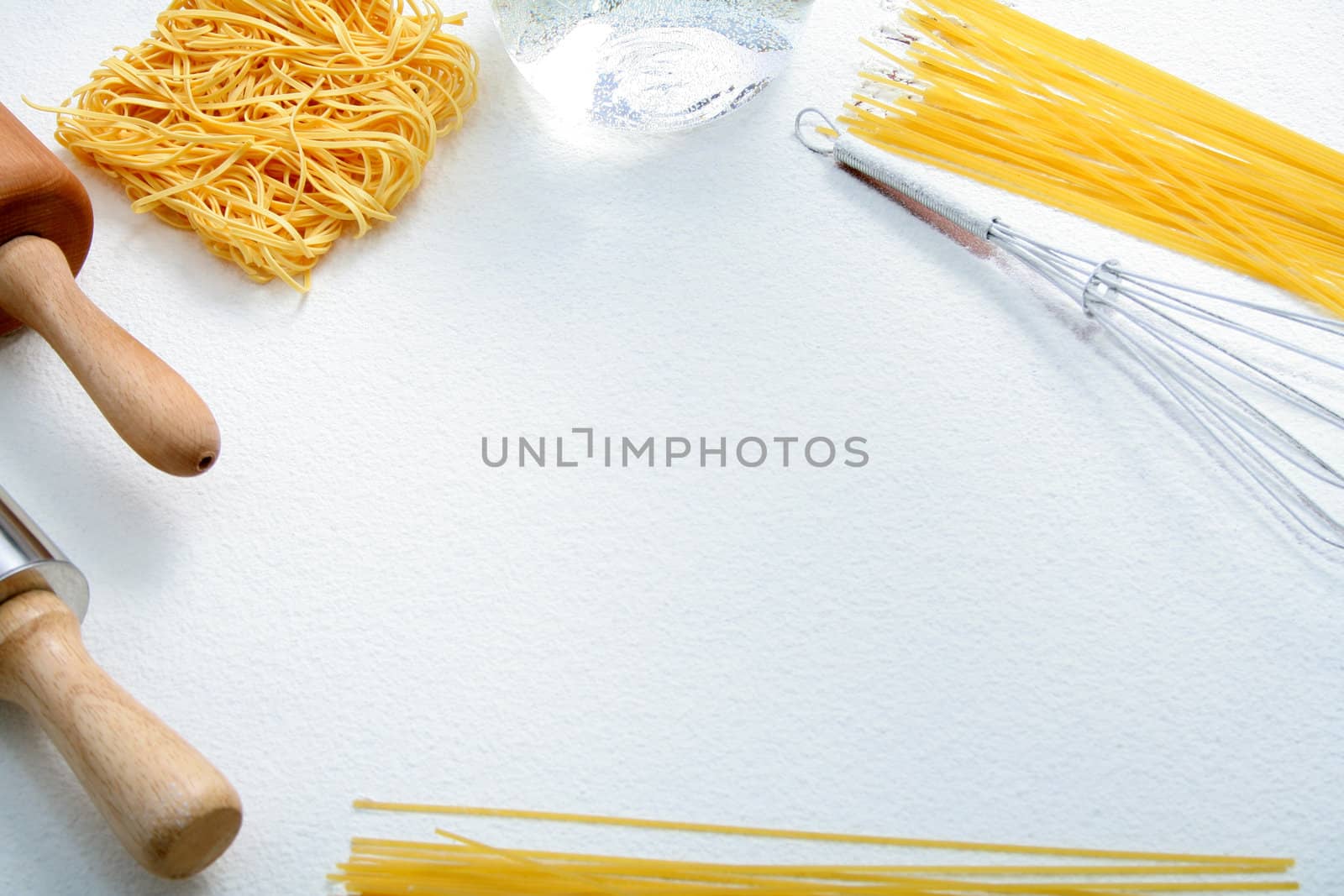 Wire whisk, macaroni and rolling pin on flour, background 