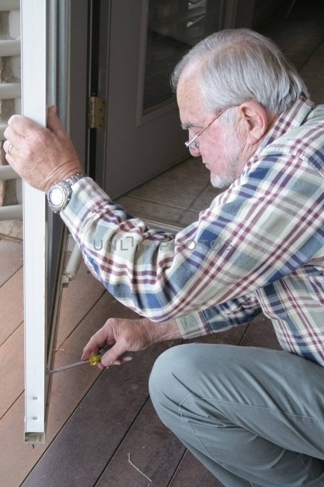 Mature Male repairing door on home