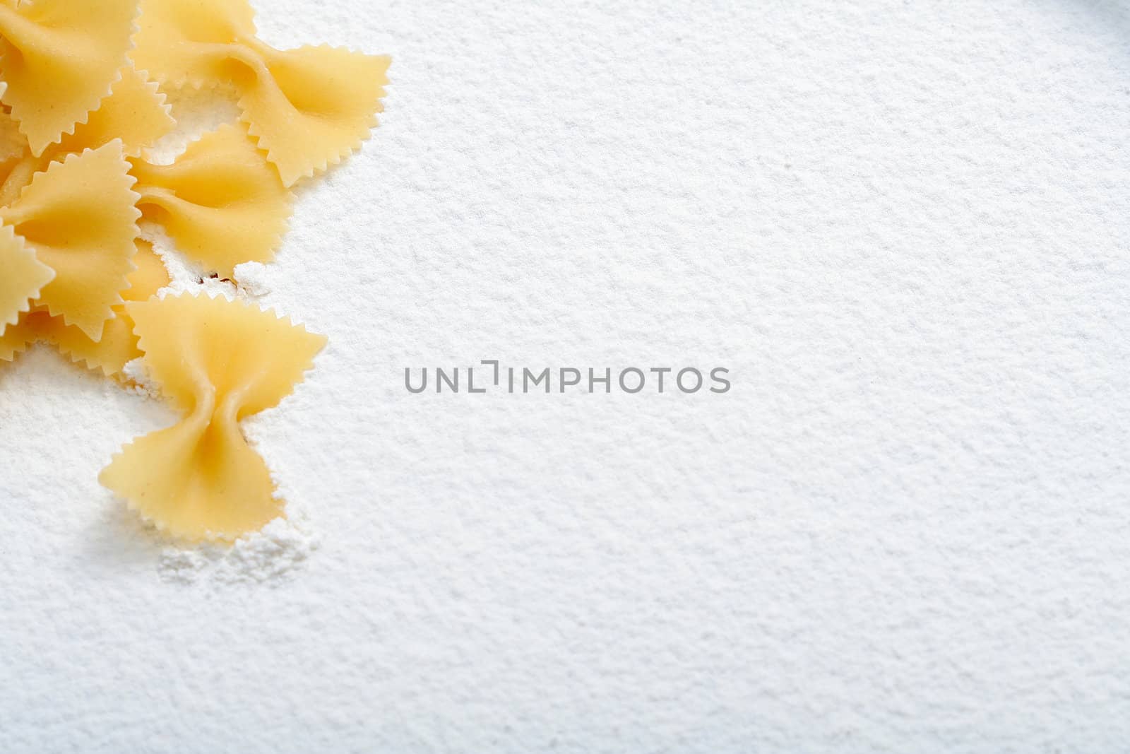 Uncooked macaroni on wheat flour, background