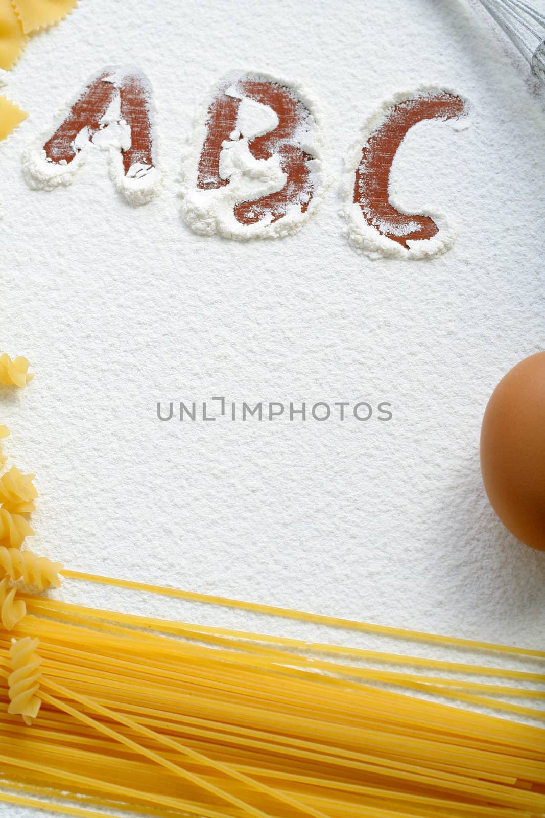 Uncooked macaroni and egg on wheat flour, background