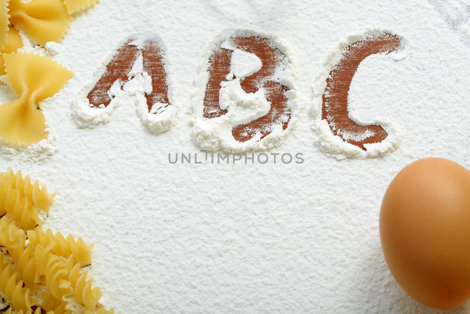 Uncooked macaroni and egg on wheat flour, background
