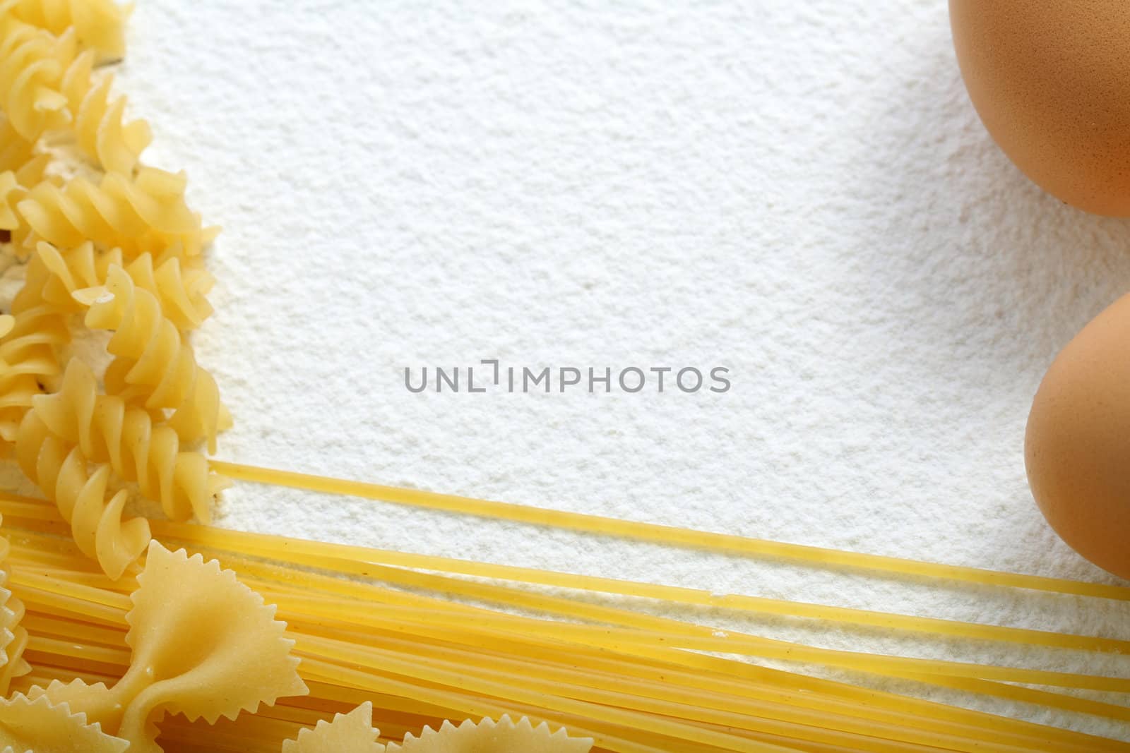 Uncooked macaroni and egg on wheat flour, background
