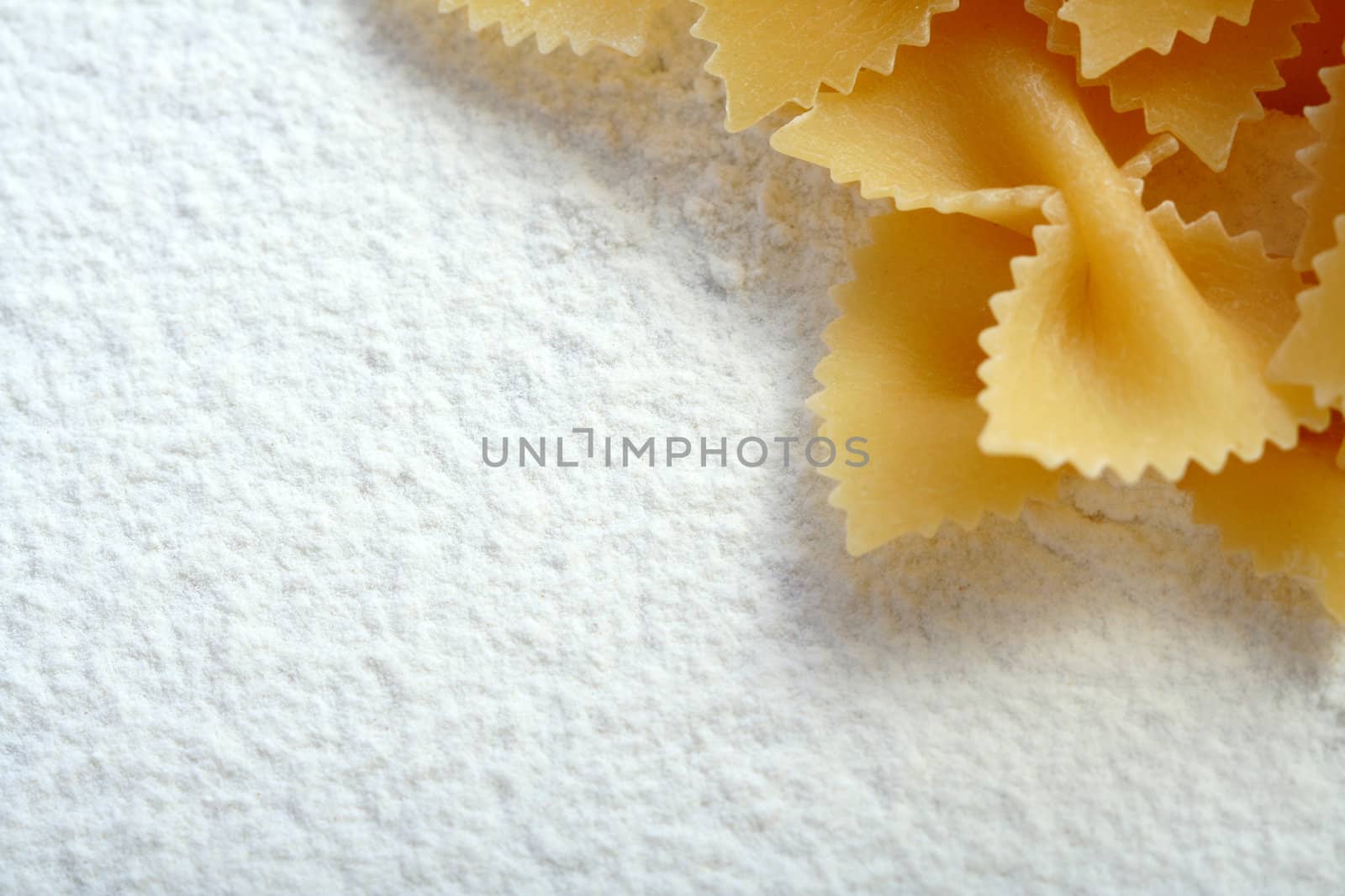 Uncooked macaroni on wheat flour, background