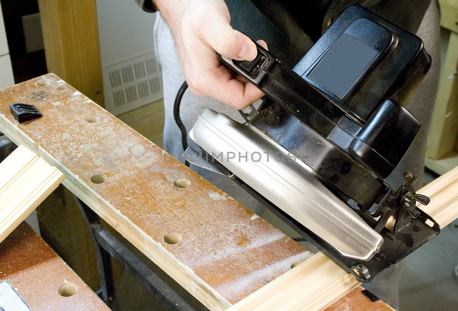 Hand holding skillsaw cutting a piece of wood