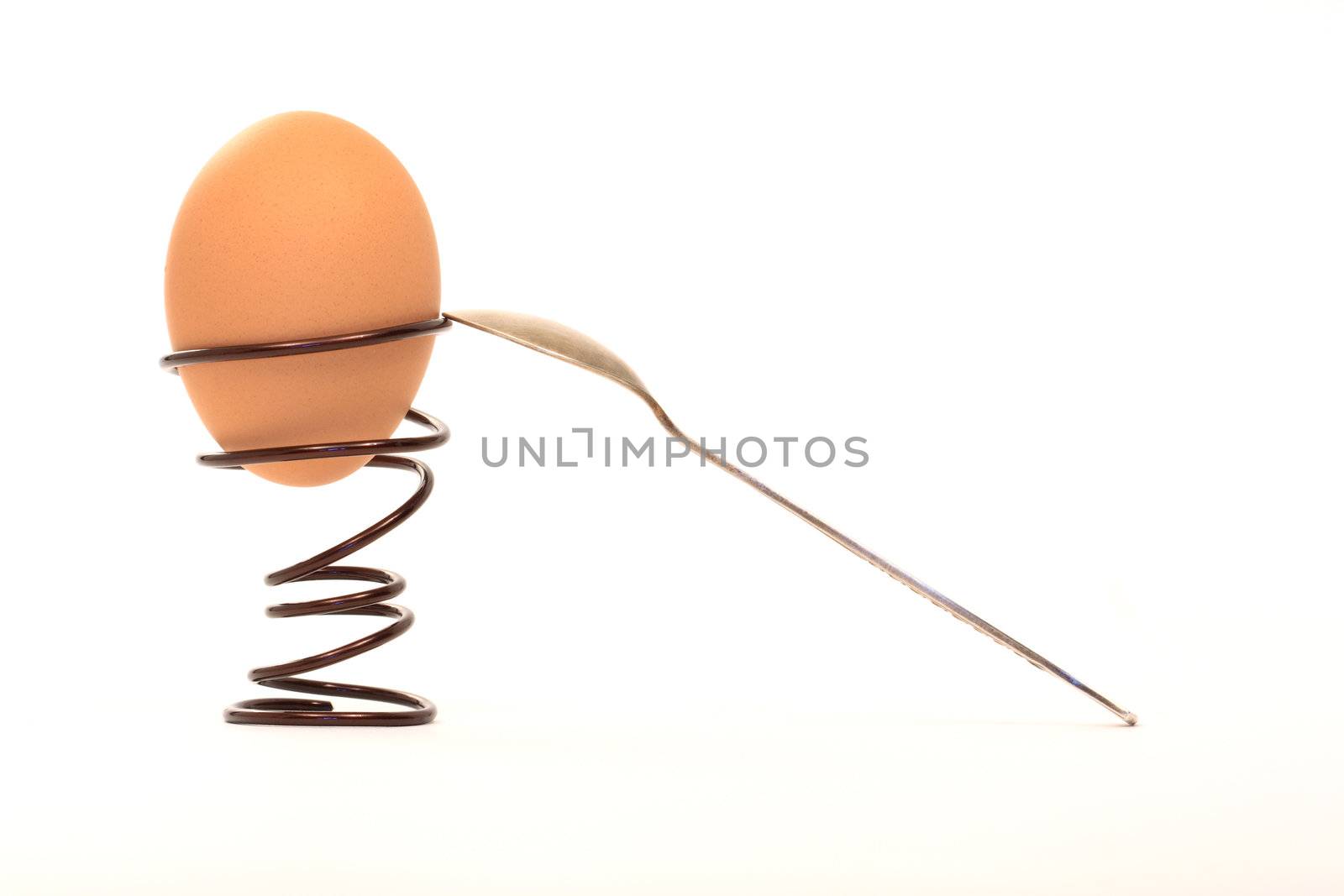 Egg inside spiral eggcup near spoon isolated on white background