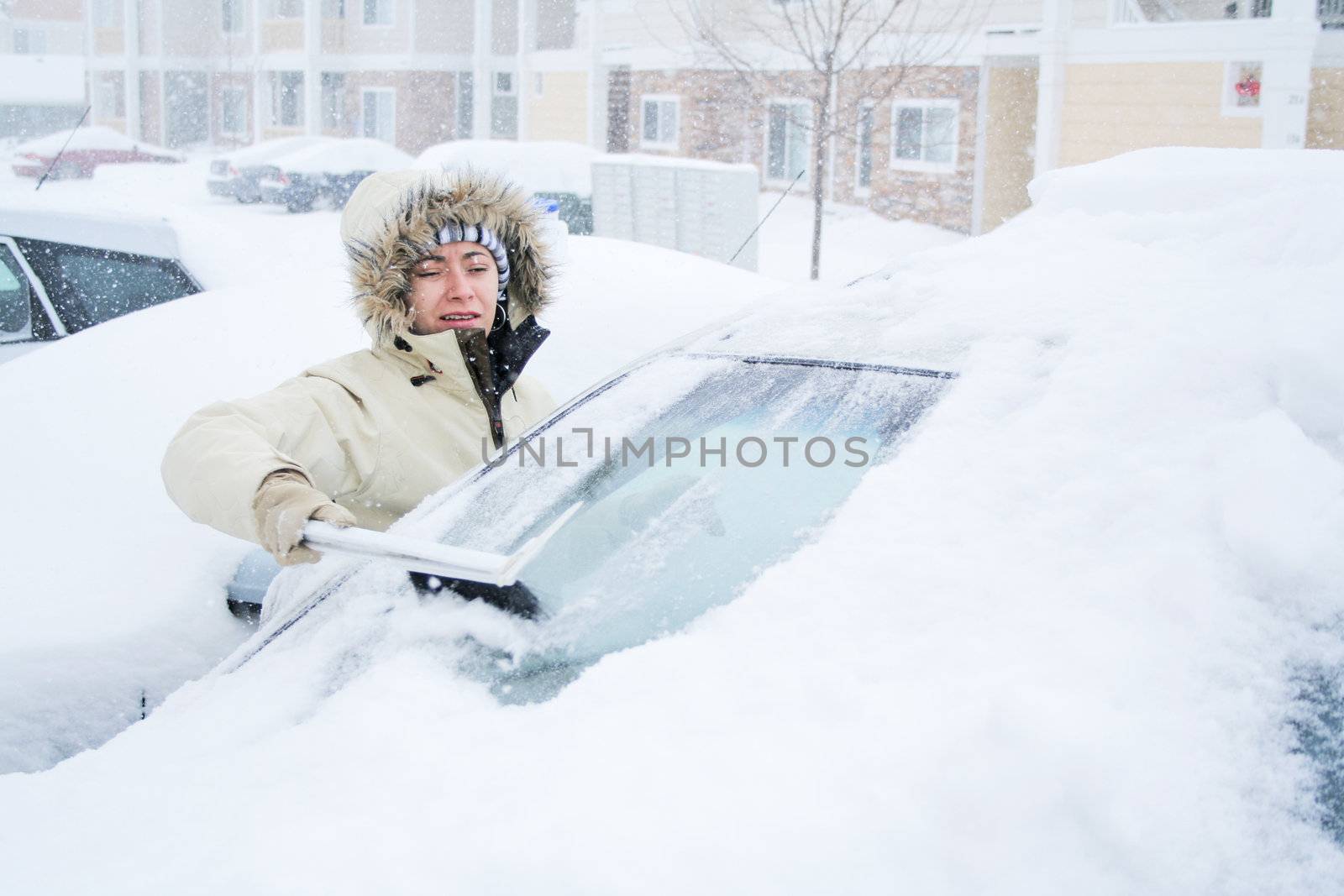 Woman scraping snow off of windshield