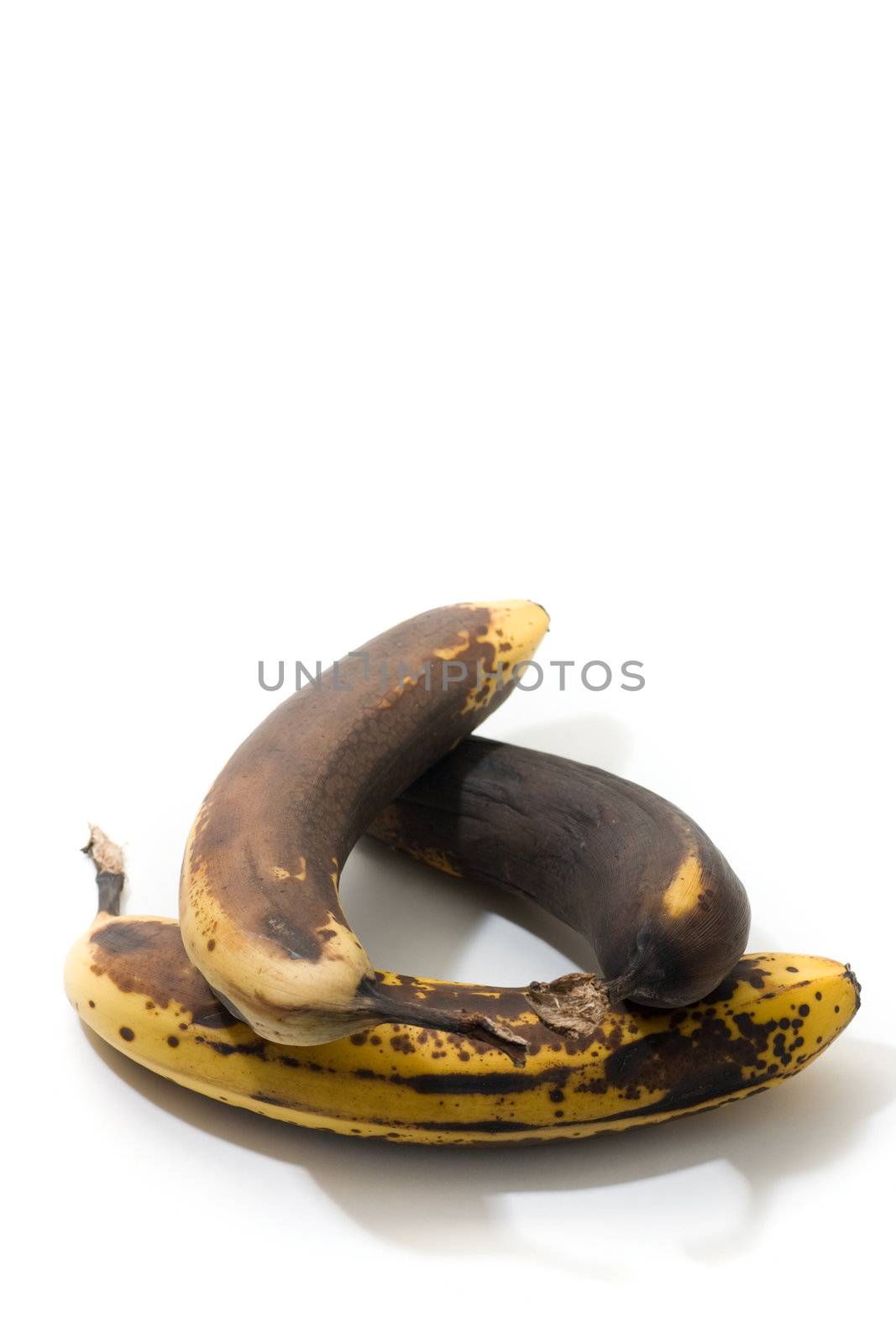 3 over-ripened bananas, arranged in a circular shape, isolated on white.