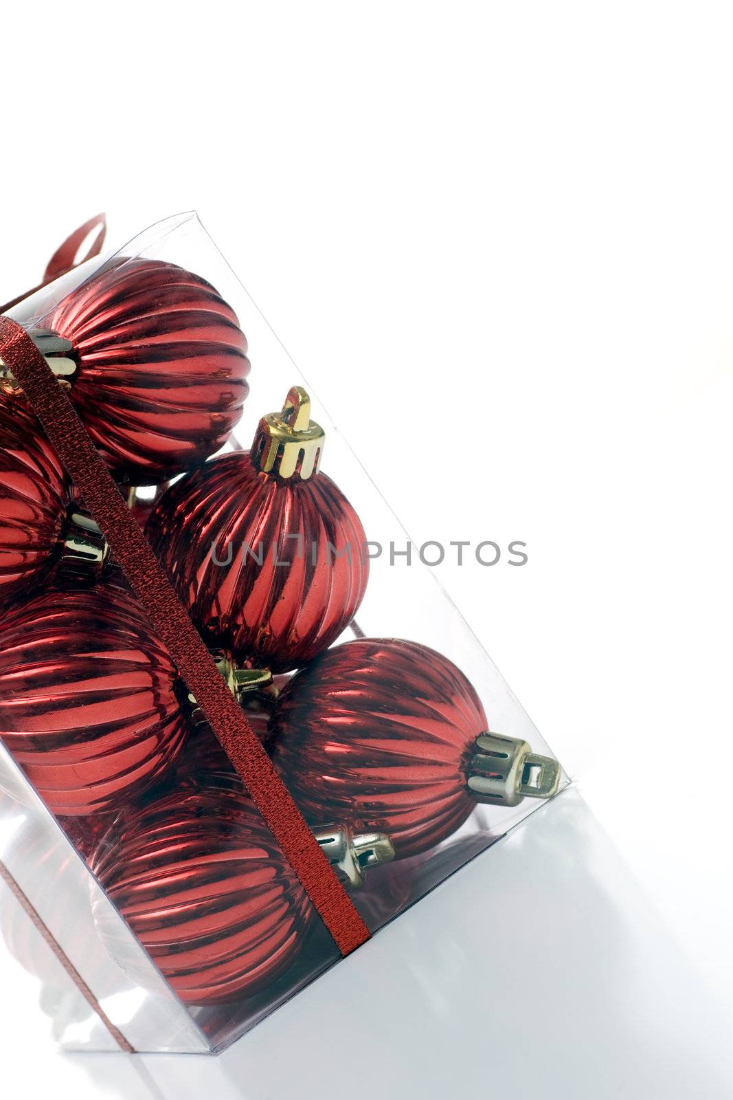A package of christmas ornaments, packaged in a clear plastic box, wrapped in ribbon, angled, and isolated on white.