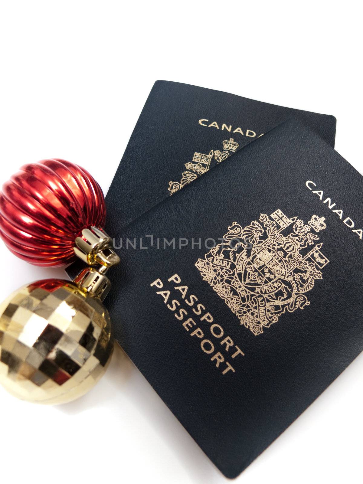Two christmas baubles beside two Canadian passports, isolated on white.