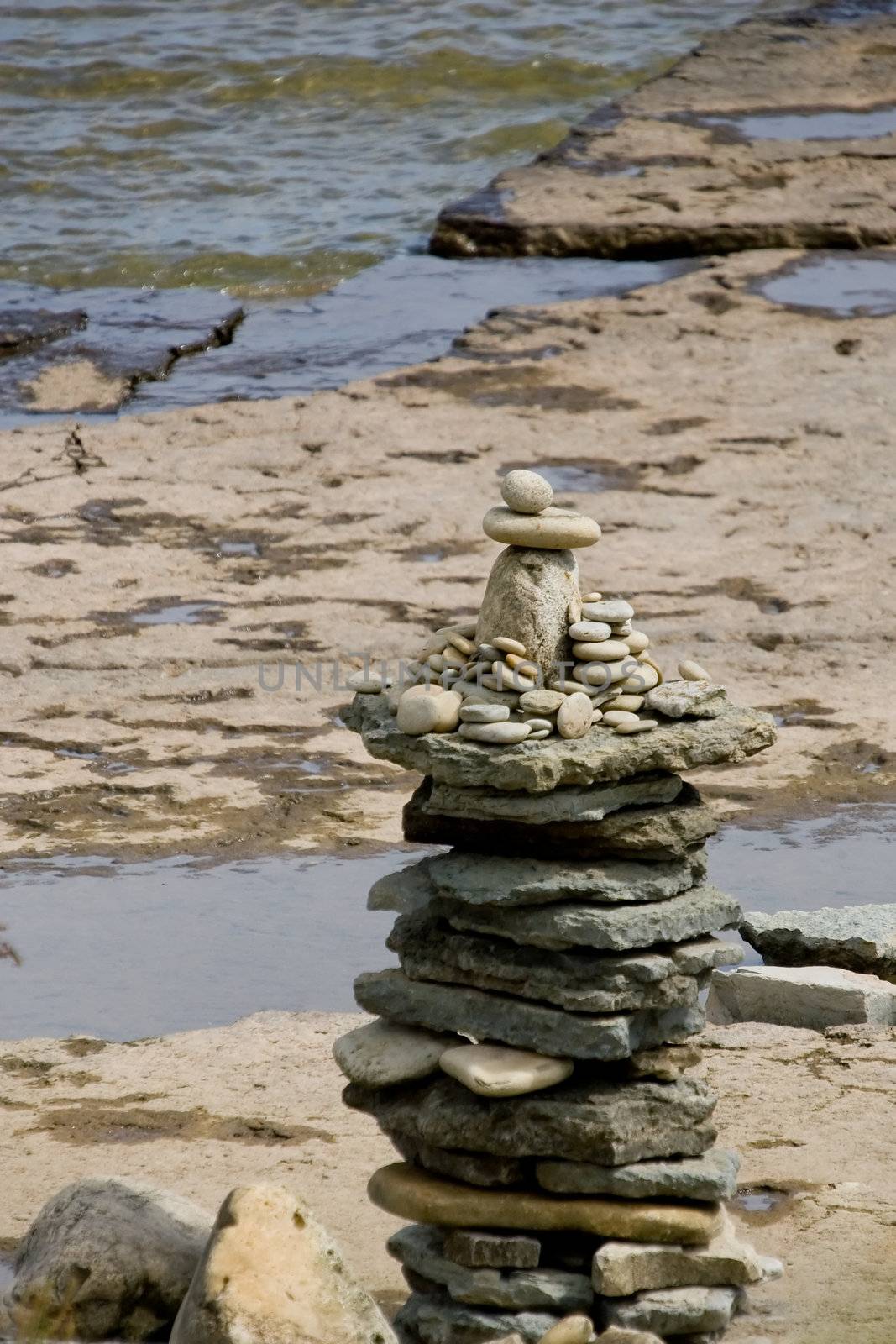 A statue of stones at the water's edge.