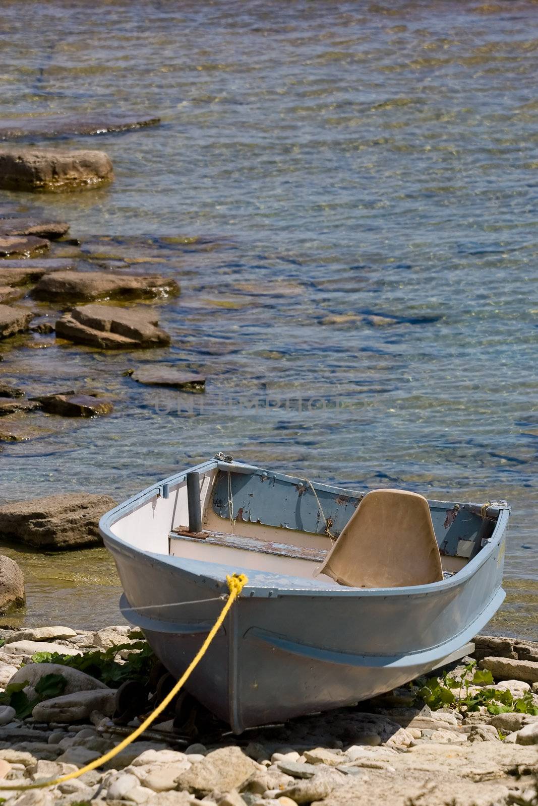 An old boat, tied up on the rocks, at the waters edge.