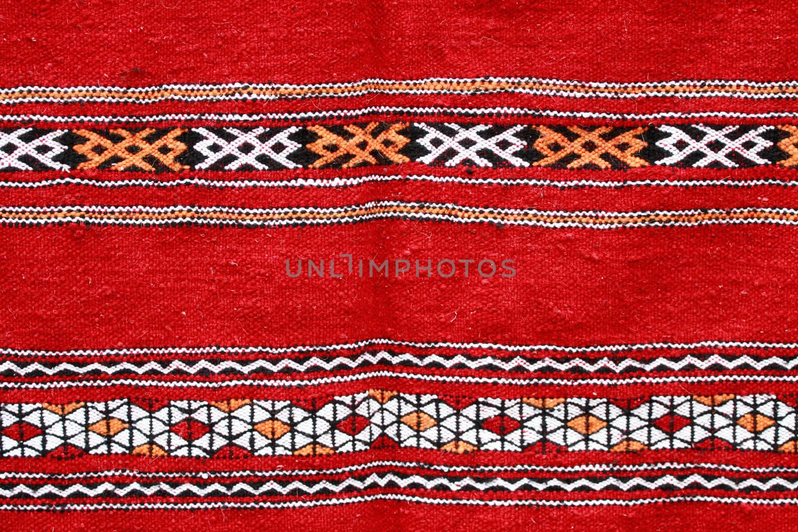 Red ethnographical handmade blanket with color pattern.