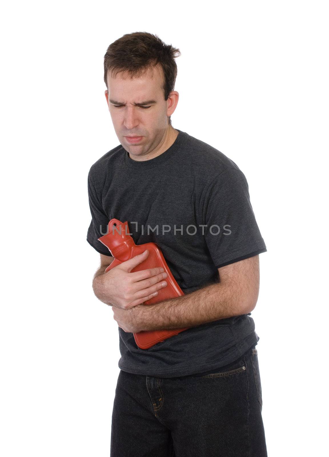 A young man with a stomach ache is holding a hot water bottle to his belly, isolated against a white background