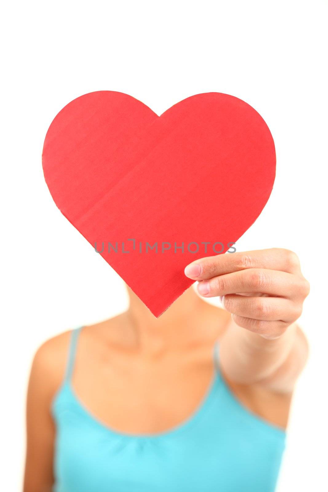 Woman holding Valentines Day heart sign with copyspace. Model isolated on white background. Shallow depth of field with focus on the heart sign.