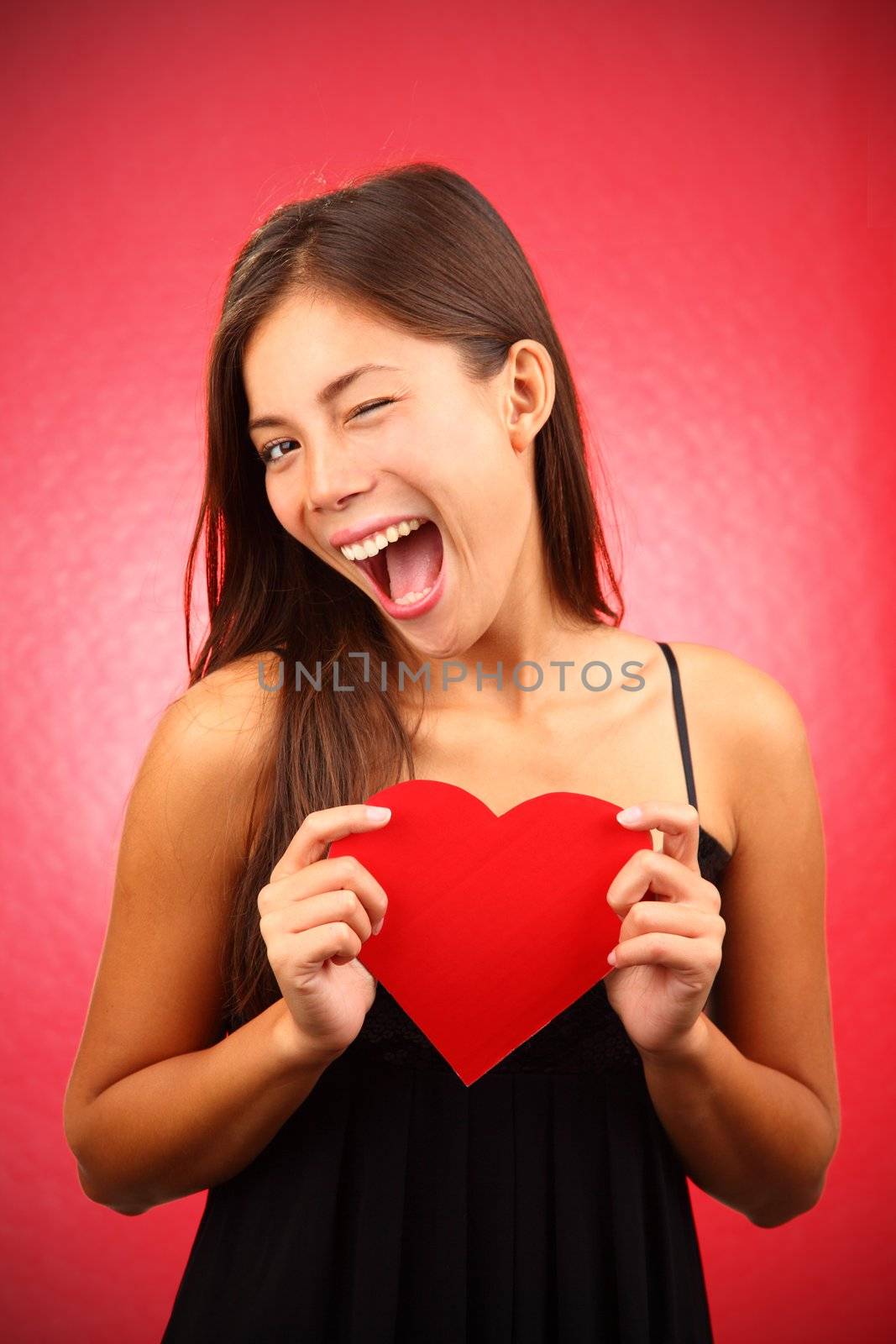 Woman holding Valentines Day heart sign. Beautiful mixed race chinese / caucasian model.
