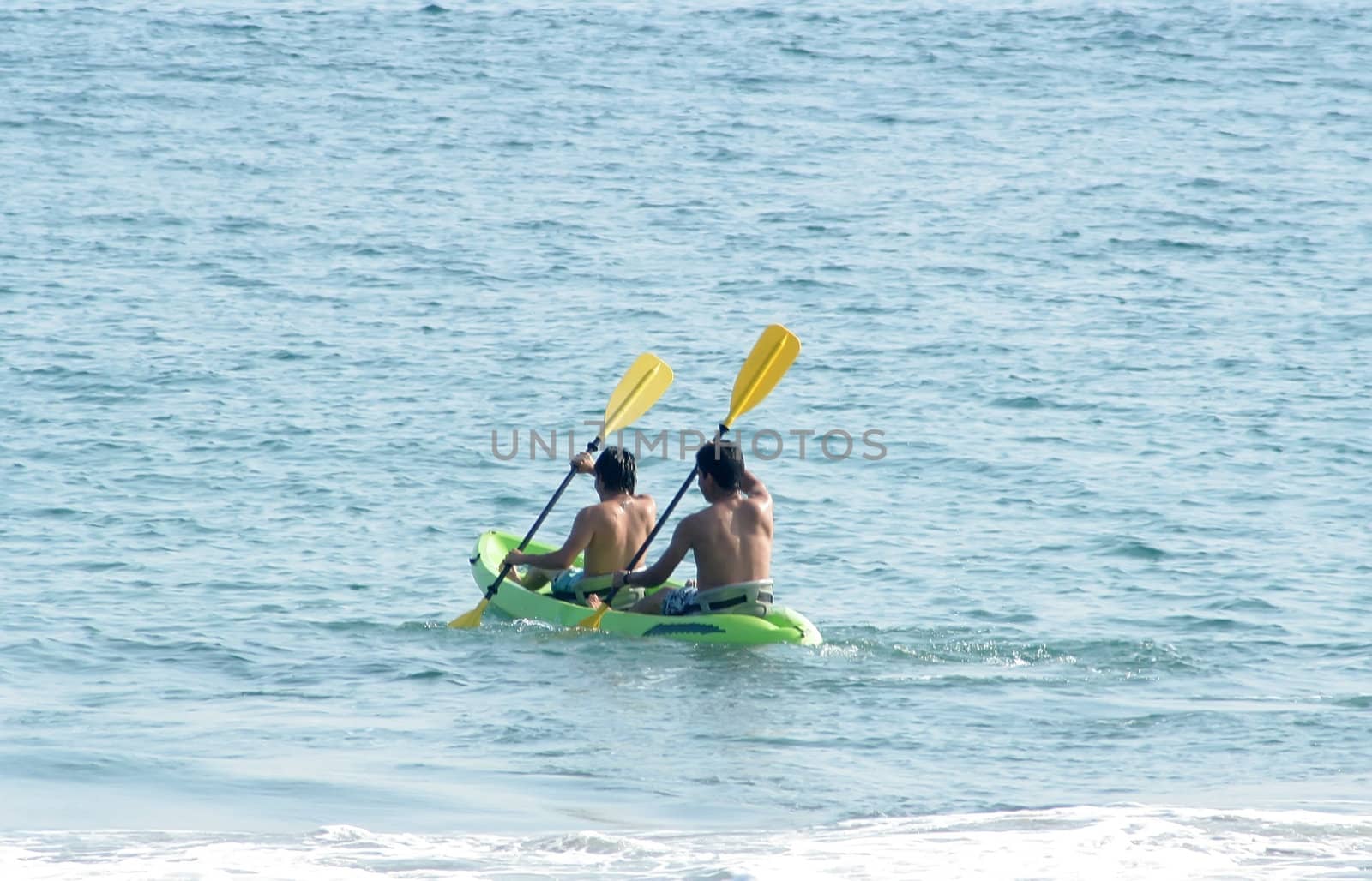 Two men rowing in sea kayak in ocean