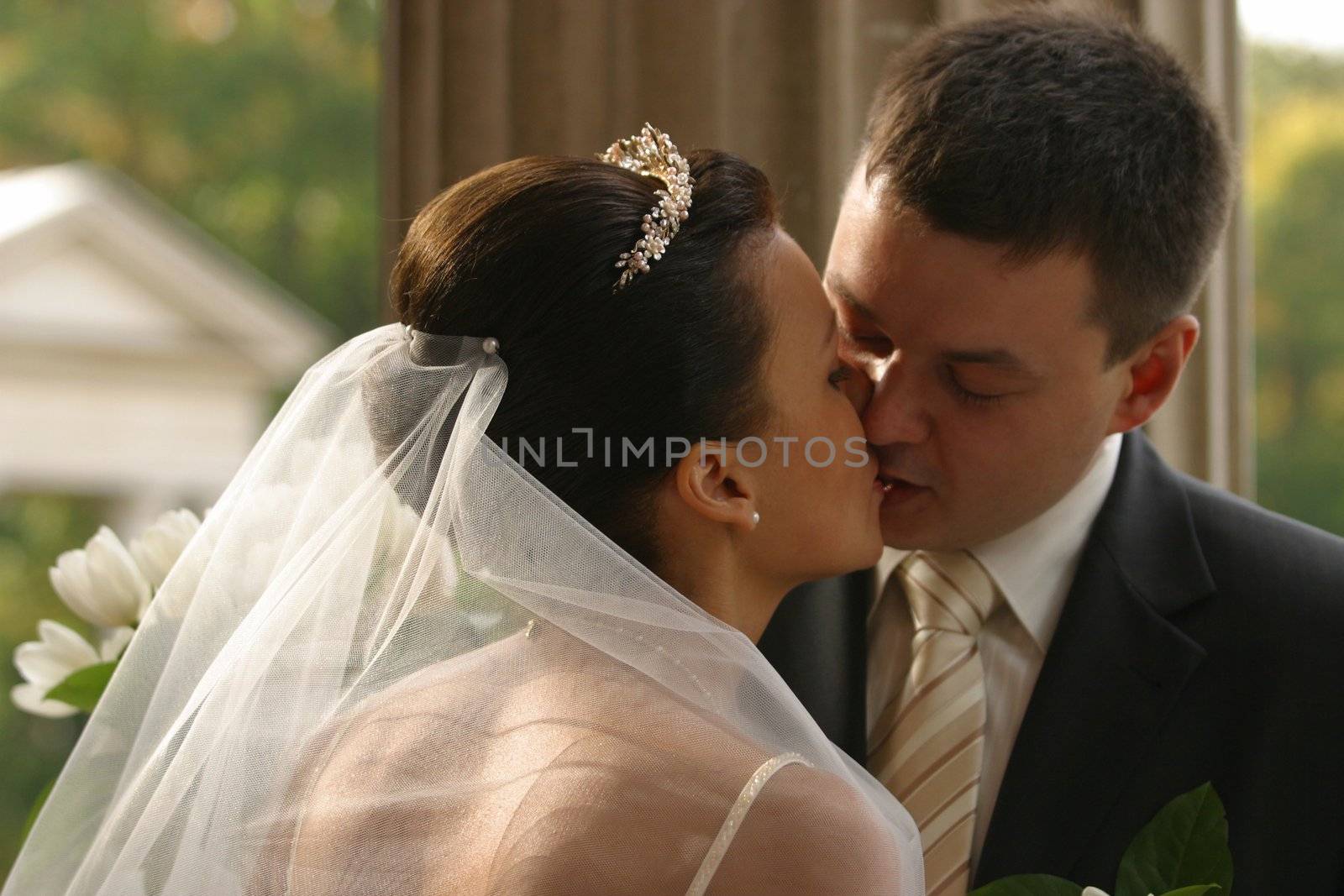 Beautiful the bride and the groom kiss at columns