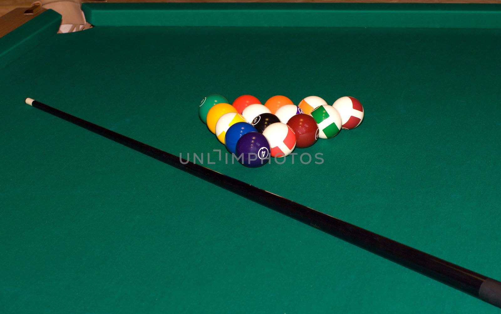 Cue and colorful billiard balls on a table of green cloth.