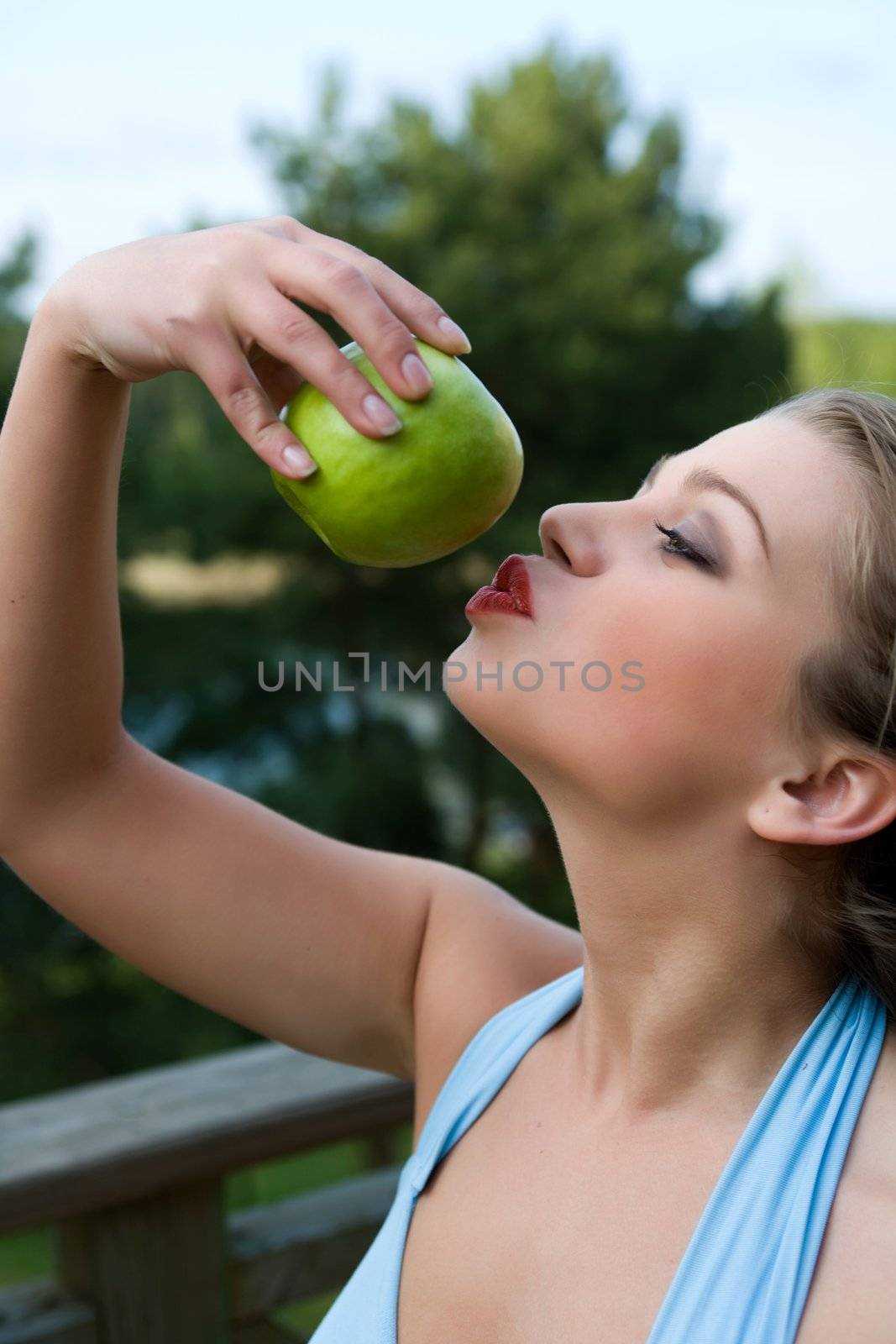 Girl with apple on sunset on green background