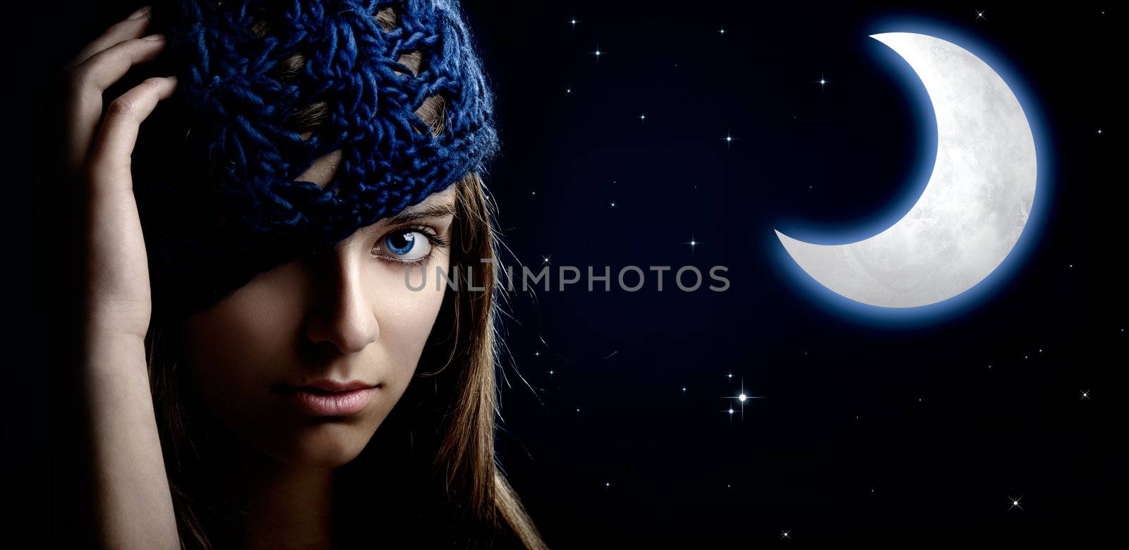 Portrait of a beautiful and young woman at night with a artifical moon on the background