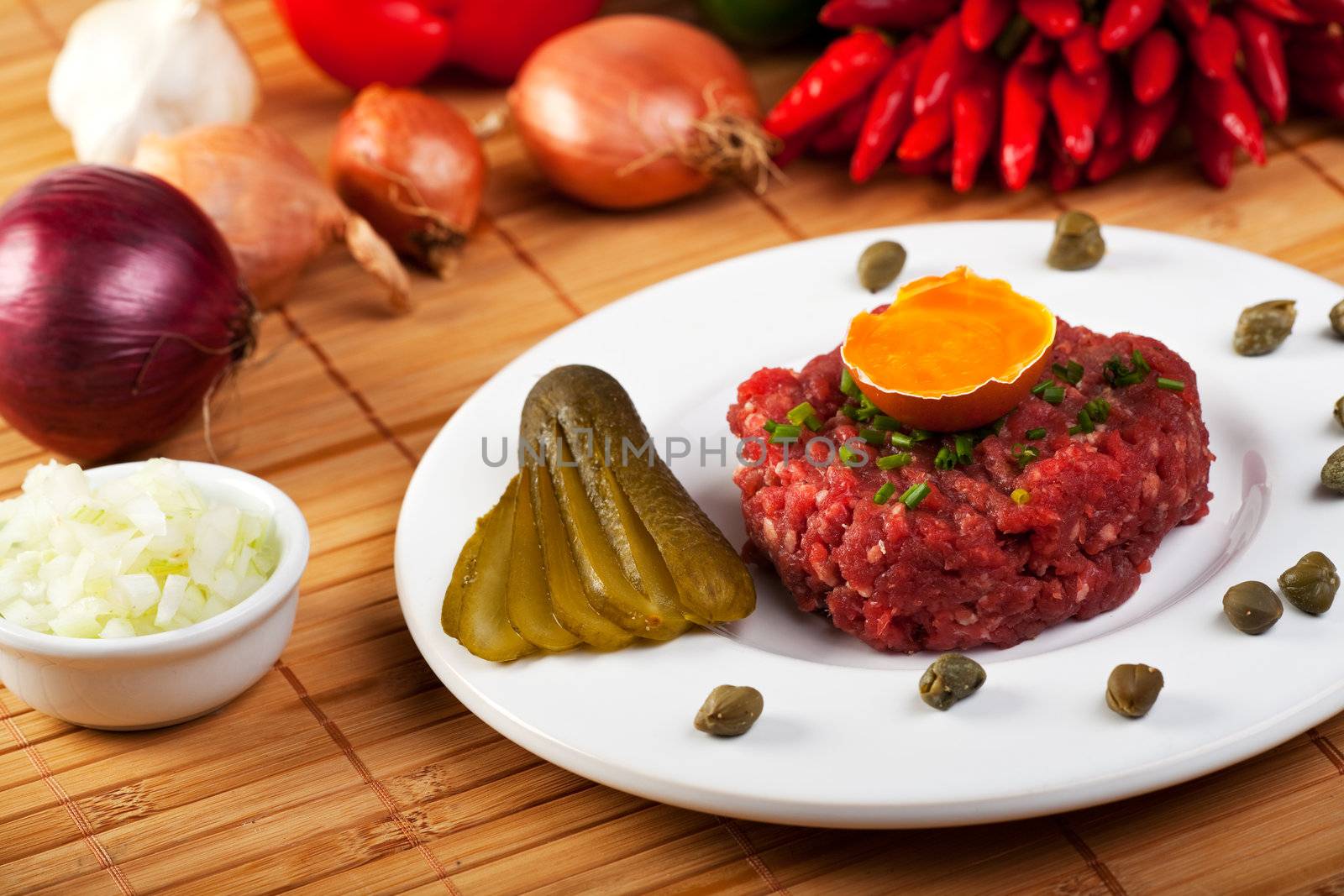 steak tartar with an onion ring and an open egg