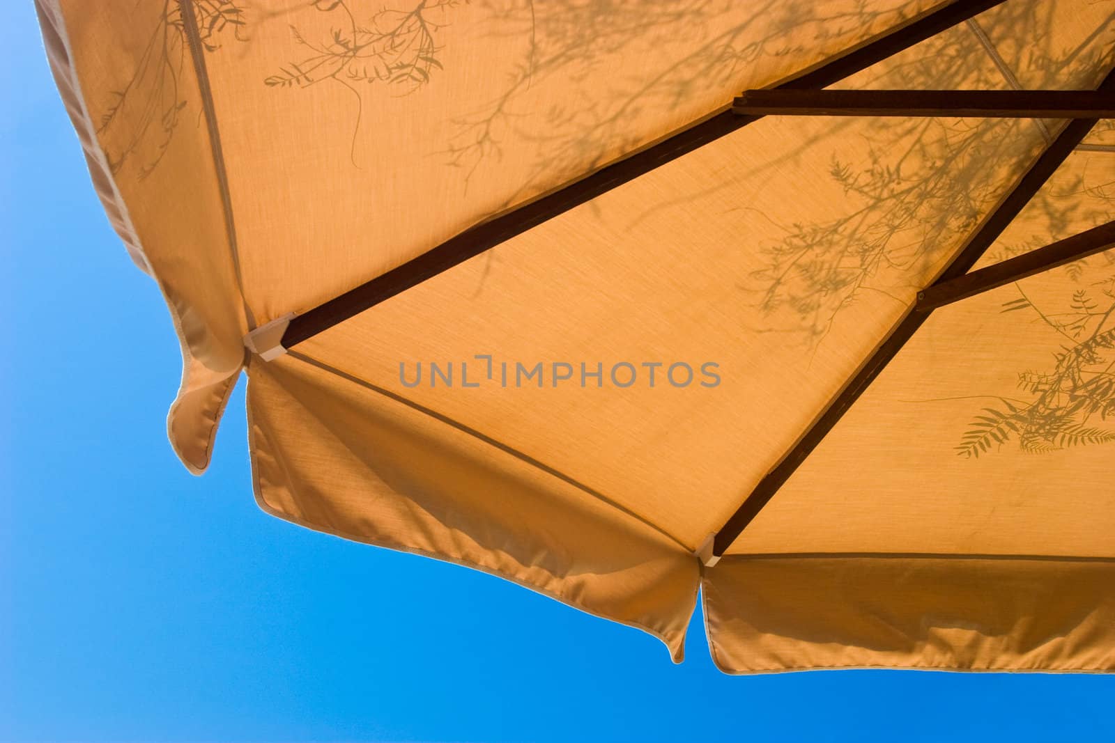 Sunshade with foliage shadows at sunny summer day