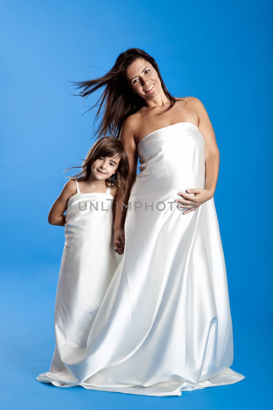 Beautiful pregnant woman with her little daughter isolated on a blue background
