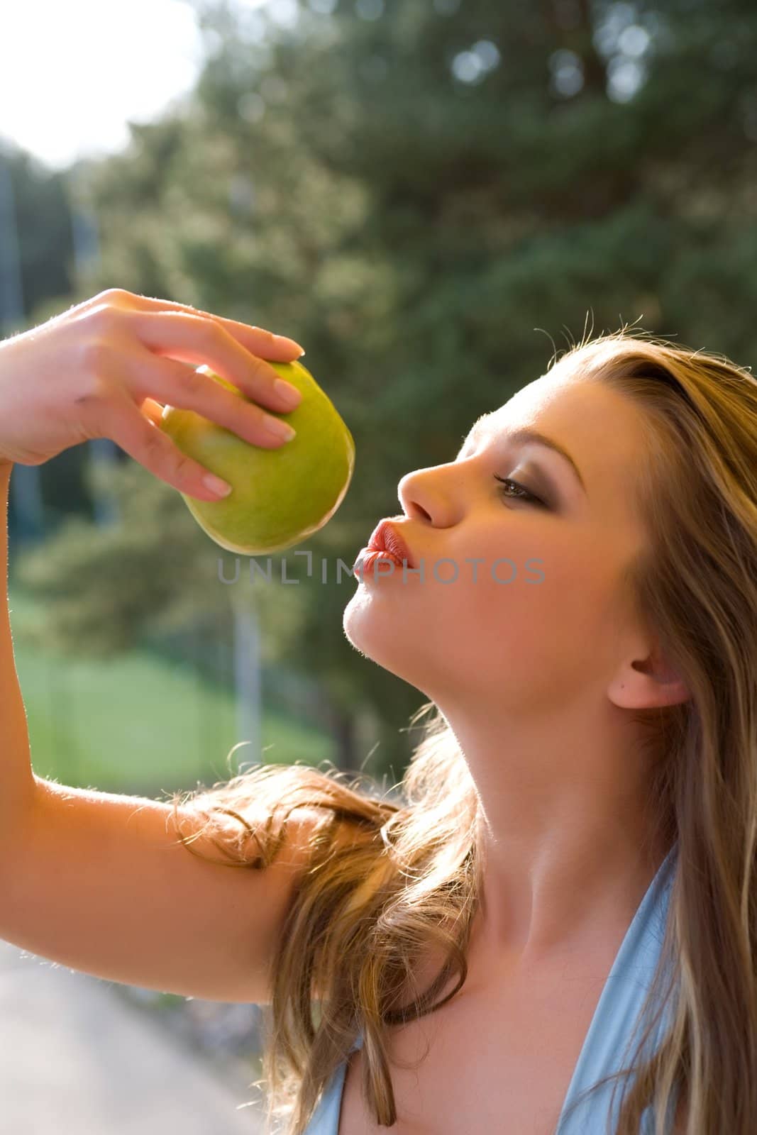 Girl with apple on sunset on green background