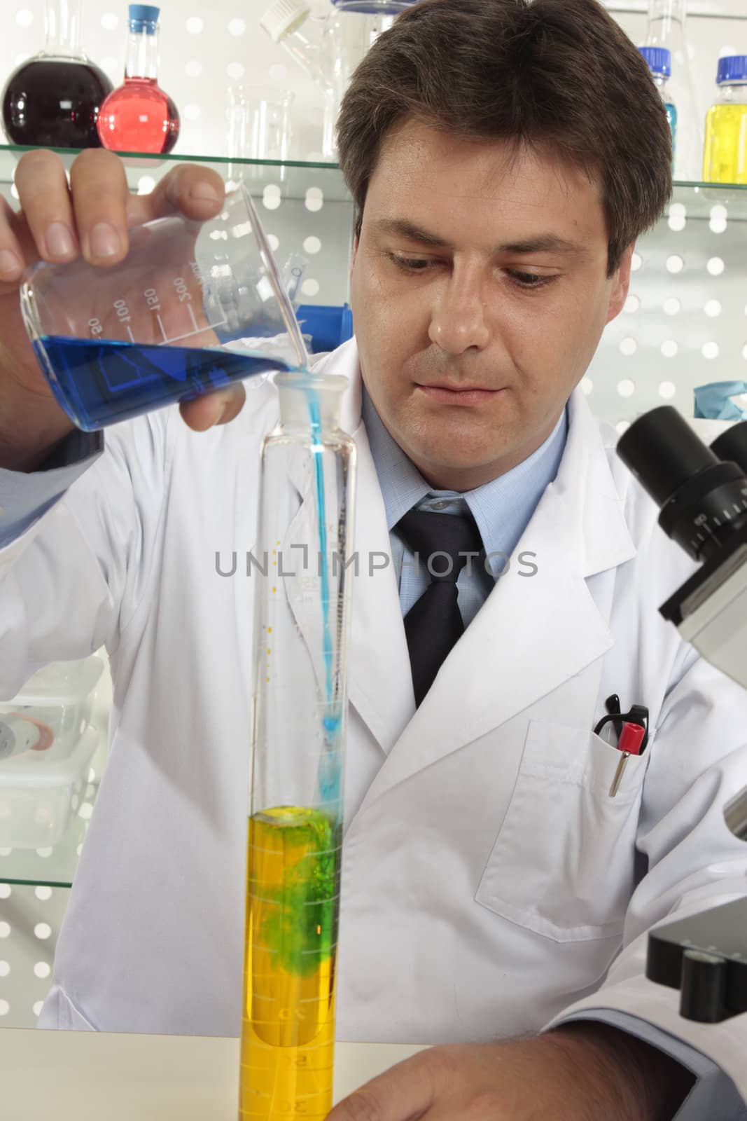 A man pouring liquid from a beaker into a large measuring cylinder