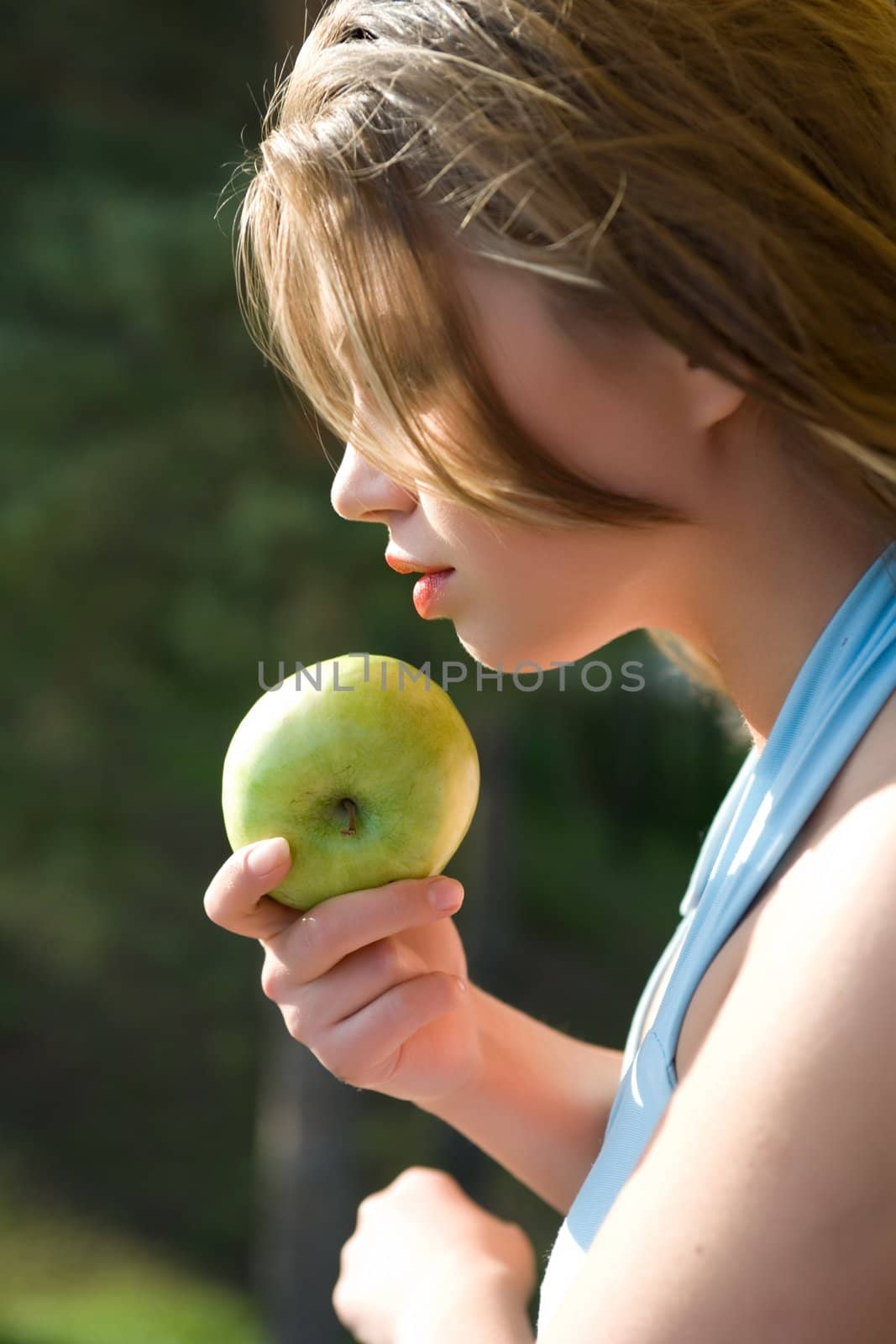 Girl with apple on sunset on green background