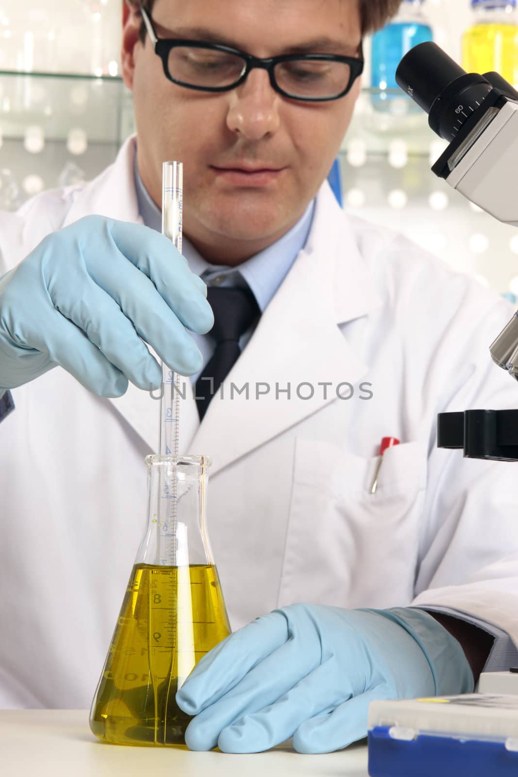 Scientist using a stirrer to mix liquids in flask.  Focus to hands and science labware.