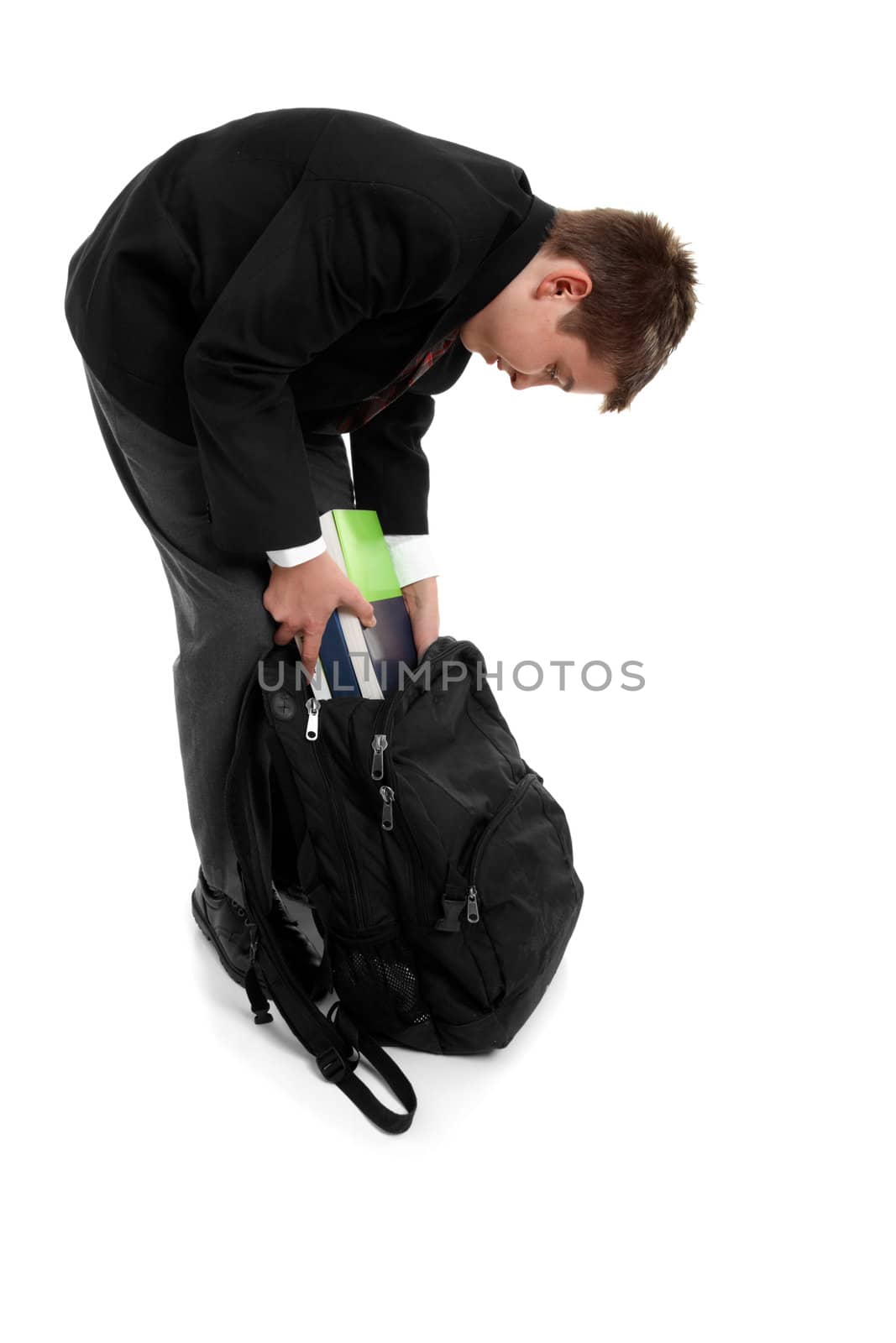 High school student placing text books in his school bag 