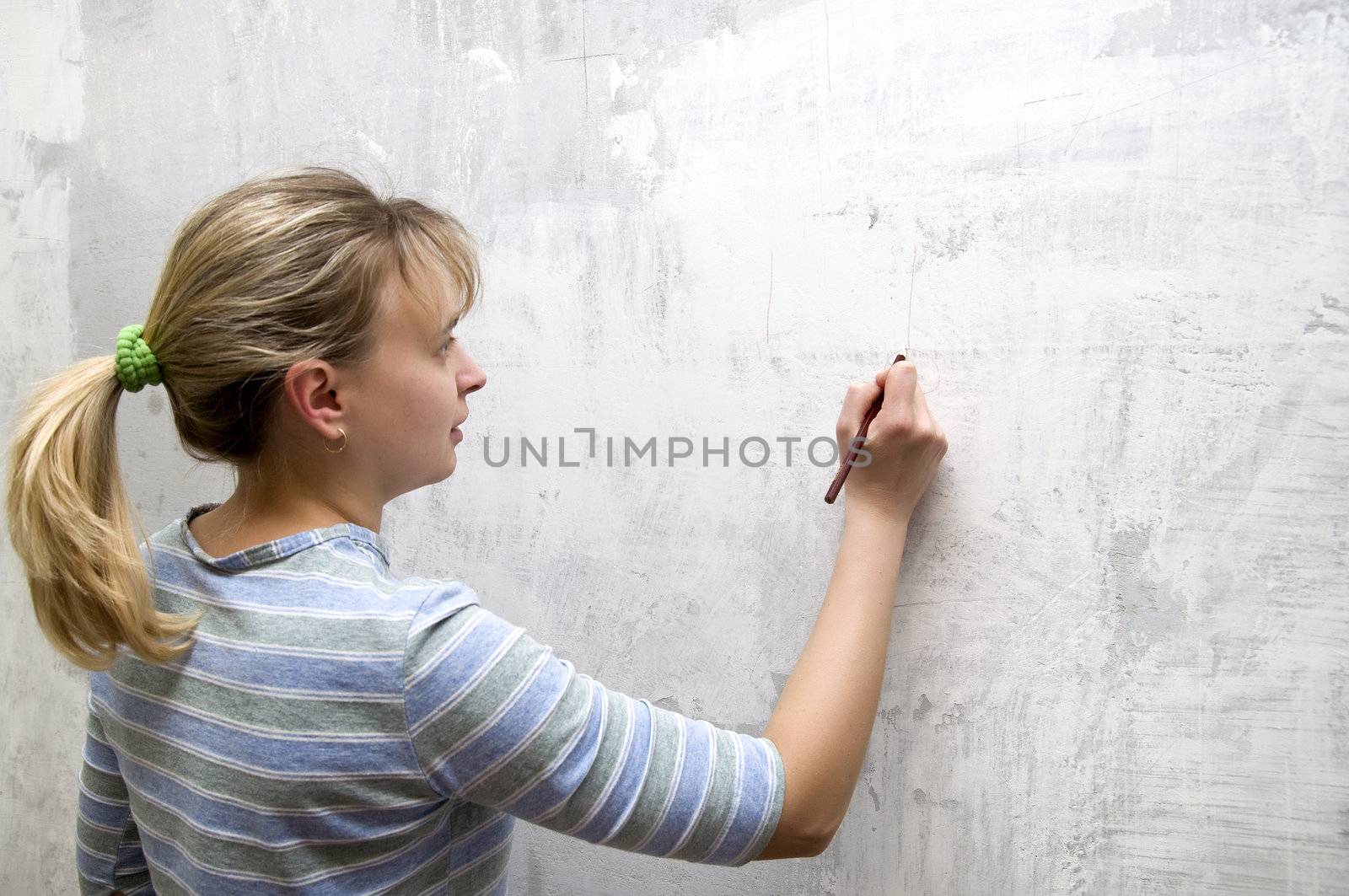 one young blonde with pencil in hands at wall