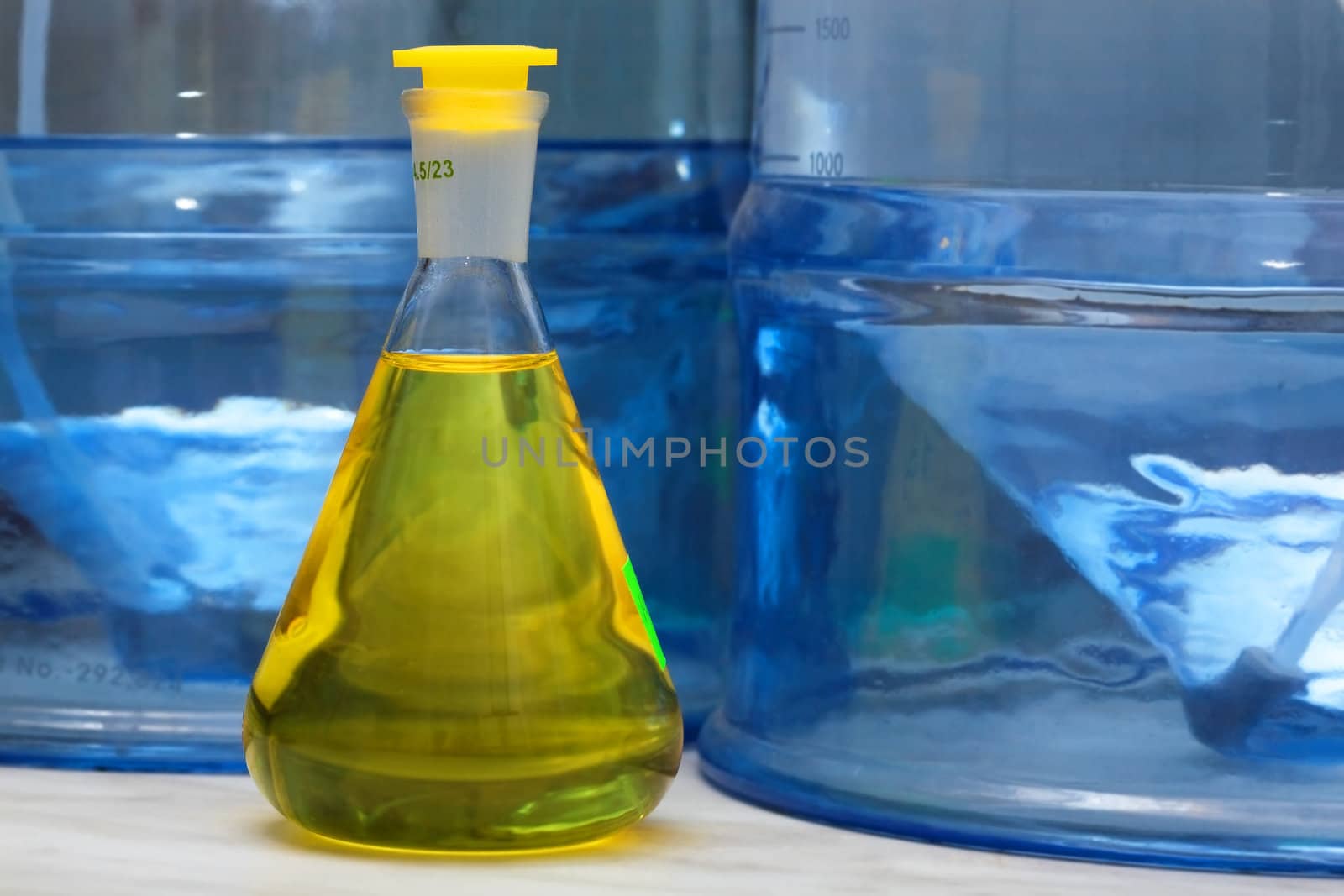 Erlenmeyer flask with yellow liquid in chemistry lab (blue background)