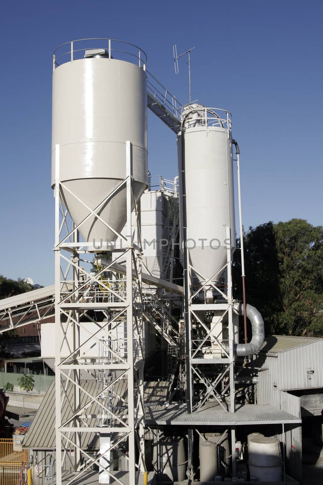 Two Industrial Silo Tanks, Manufacturing Conveyor Belt, Clear Blue Sky Background