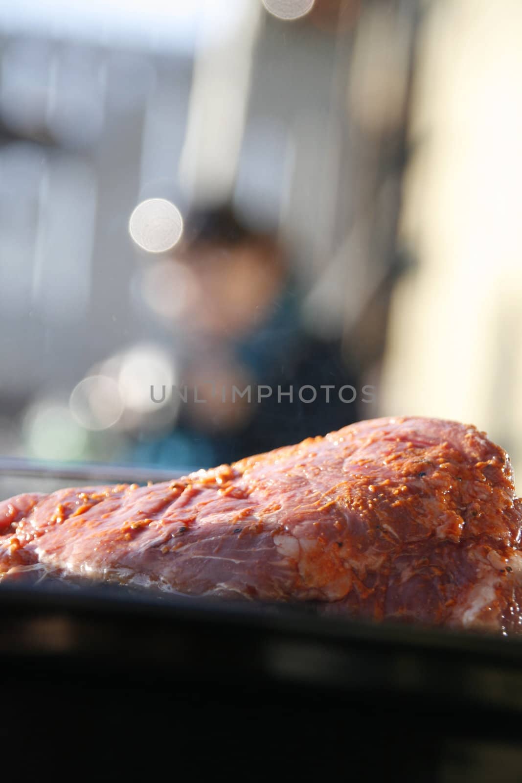 Raw meat on BBQ. Hungry woman in the back. 